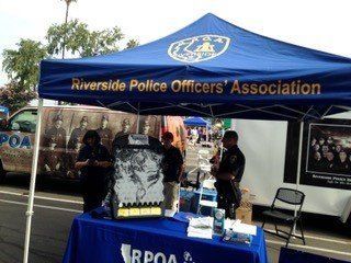 Riverside Police Officers' Association tent at an outdoor event, officers present, blue canopy, tables, and a van.