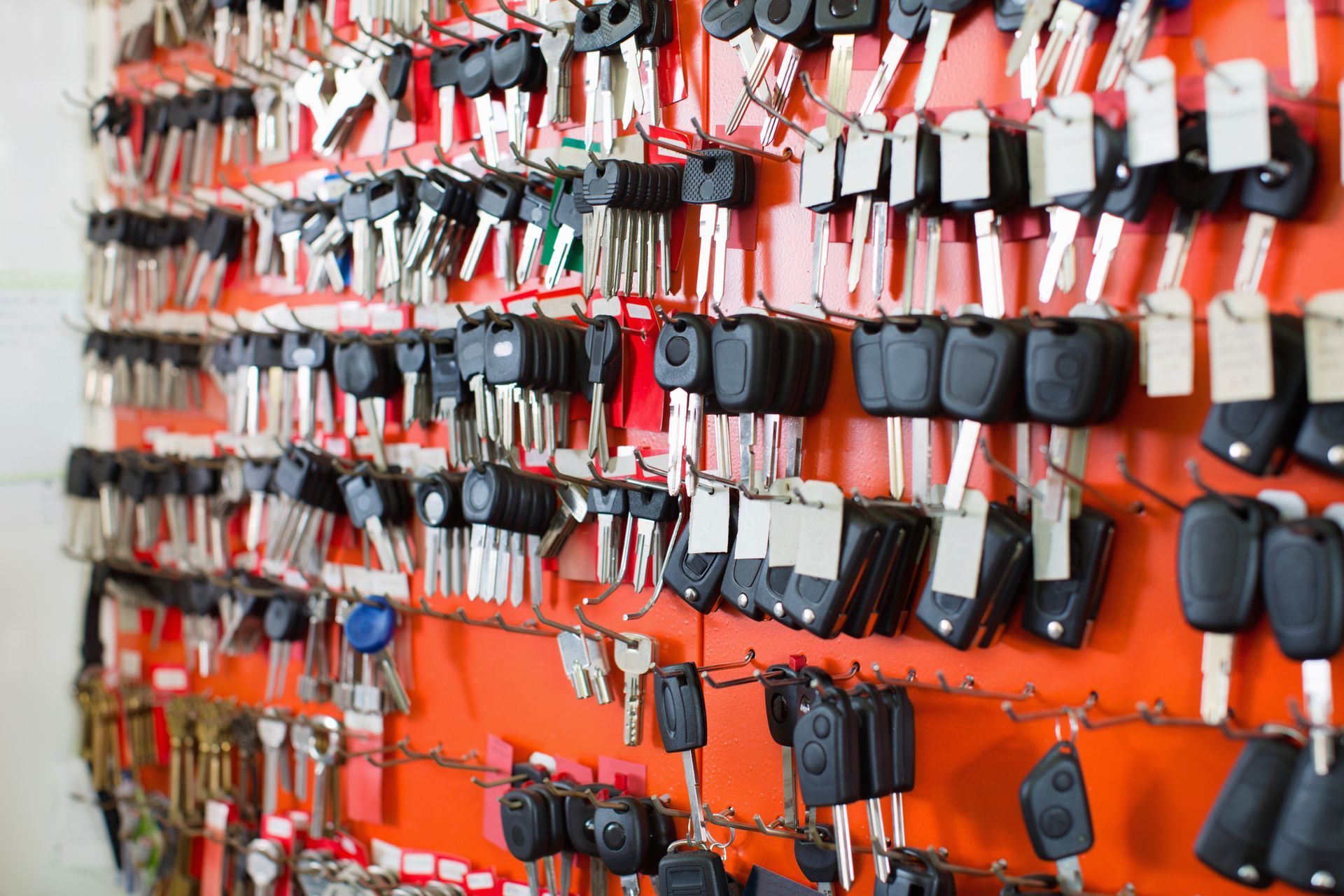 Keys hanging on a bright orange wall, organized on rows of hooks.