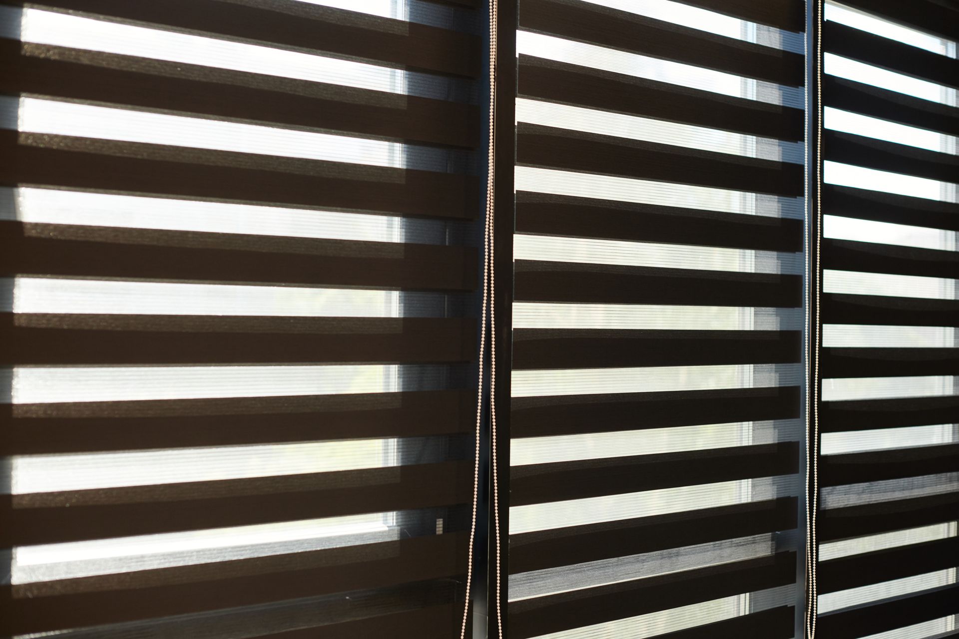 A close up of a window with zebra blinds on it.
