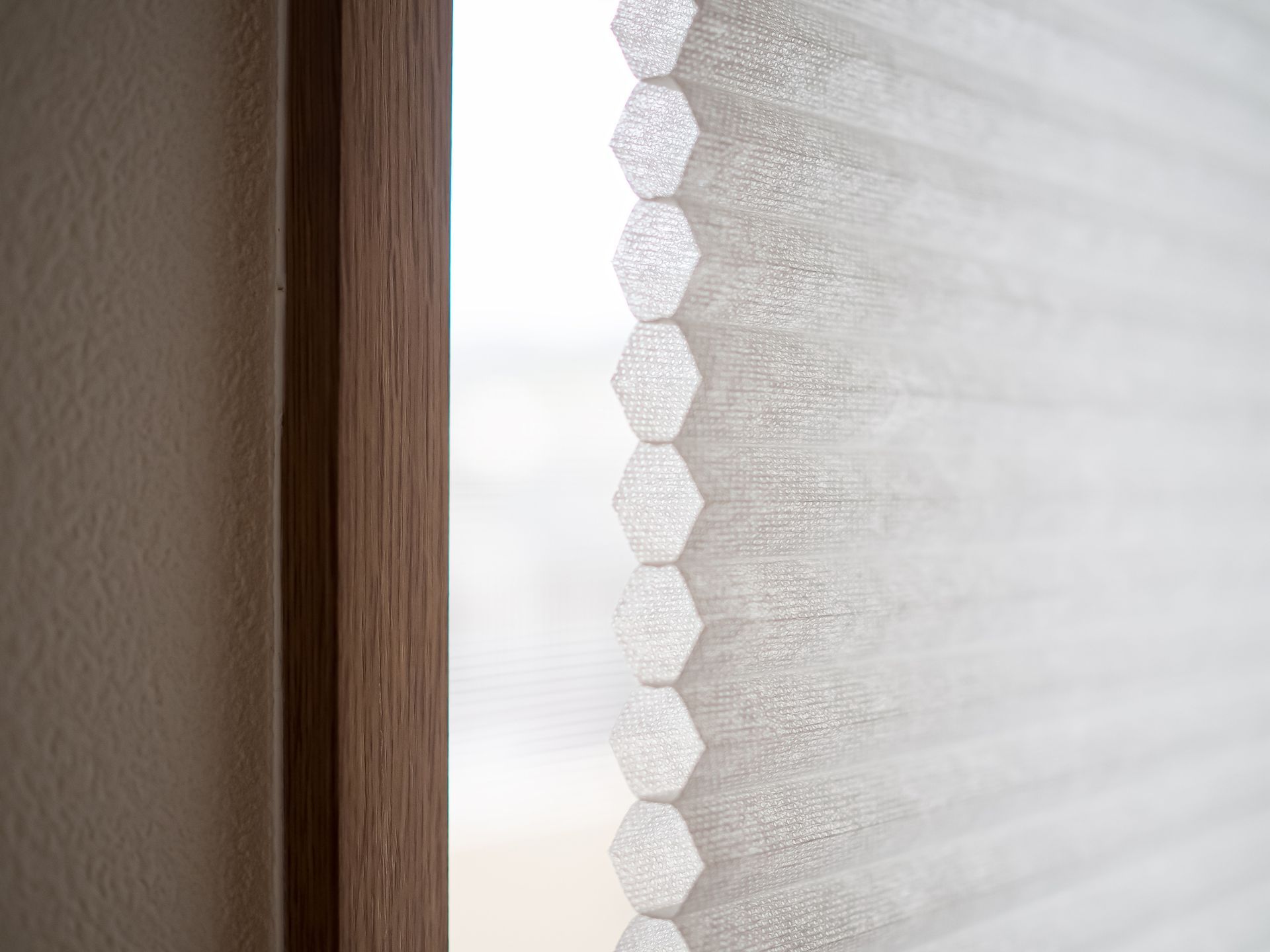 A close up of a honeycomb blind on a window.