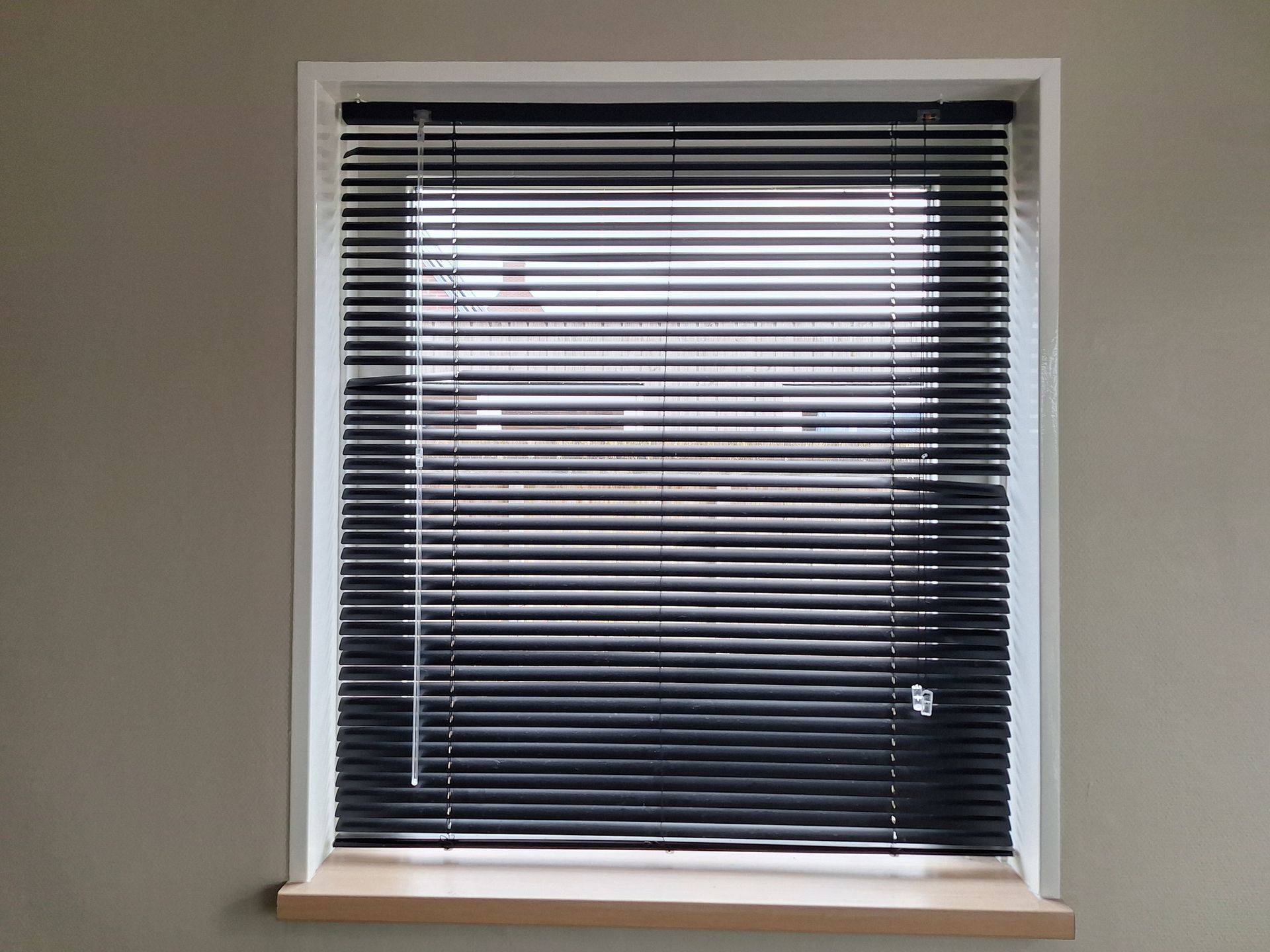 A window with black blinds on it and a white frame