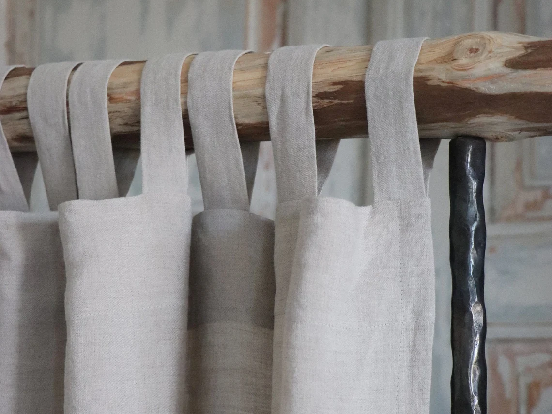 A pair of white curtains hanging on a wooden pole