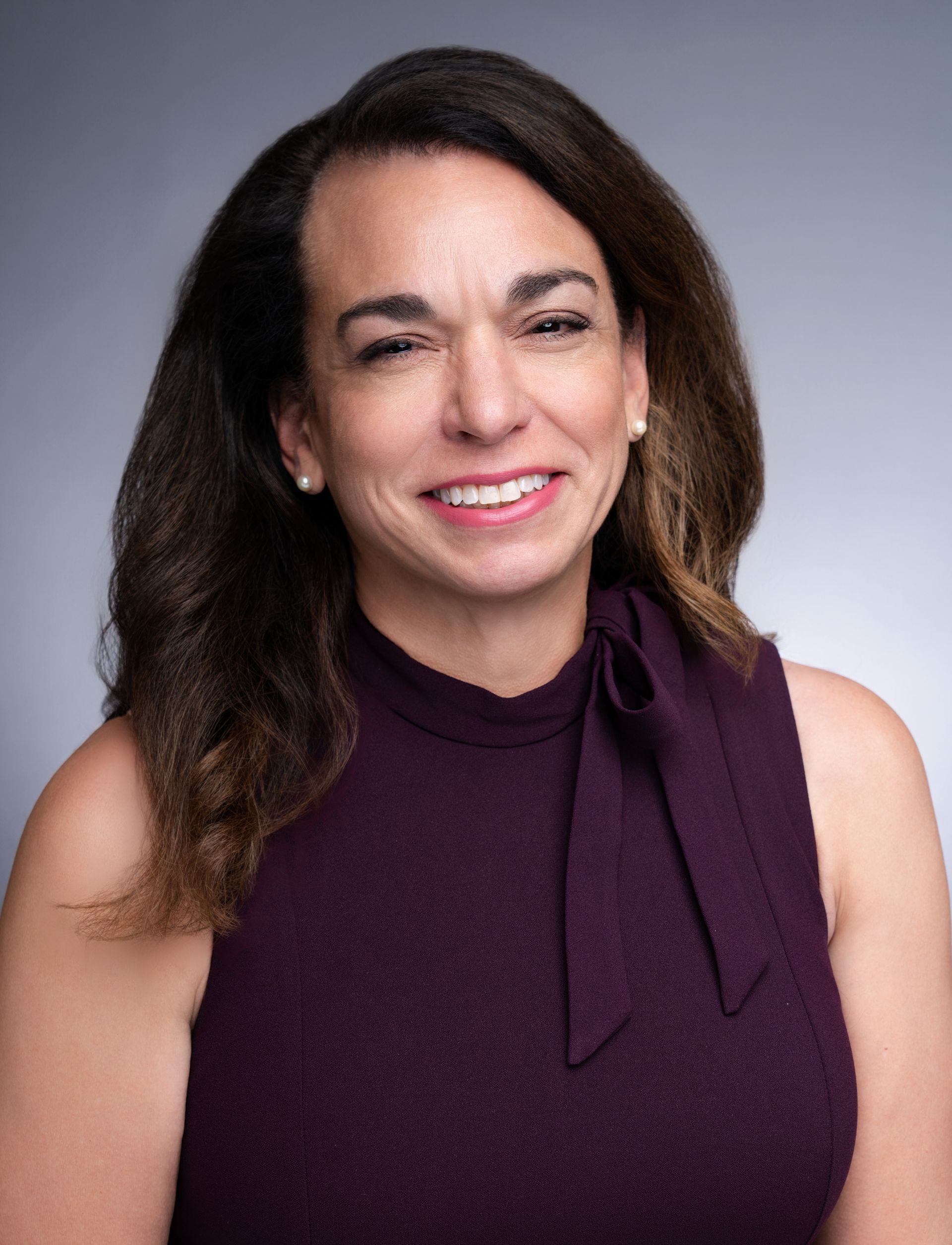 A woman in a purple dress is smiling for the camera.