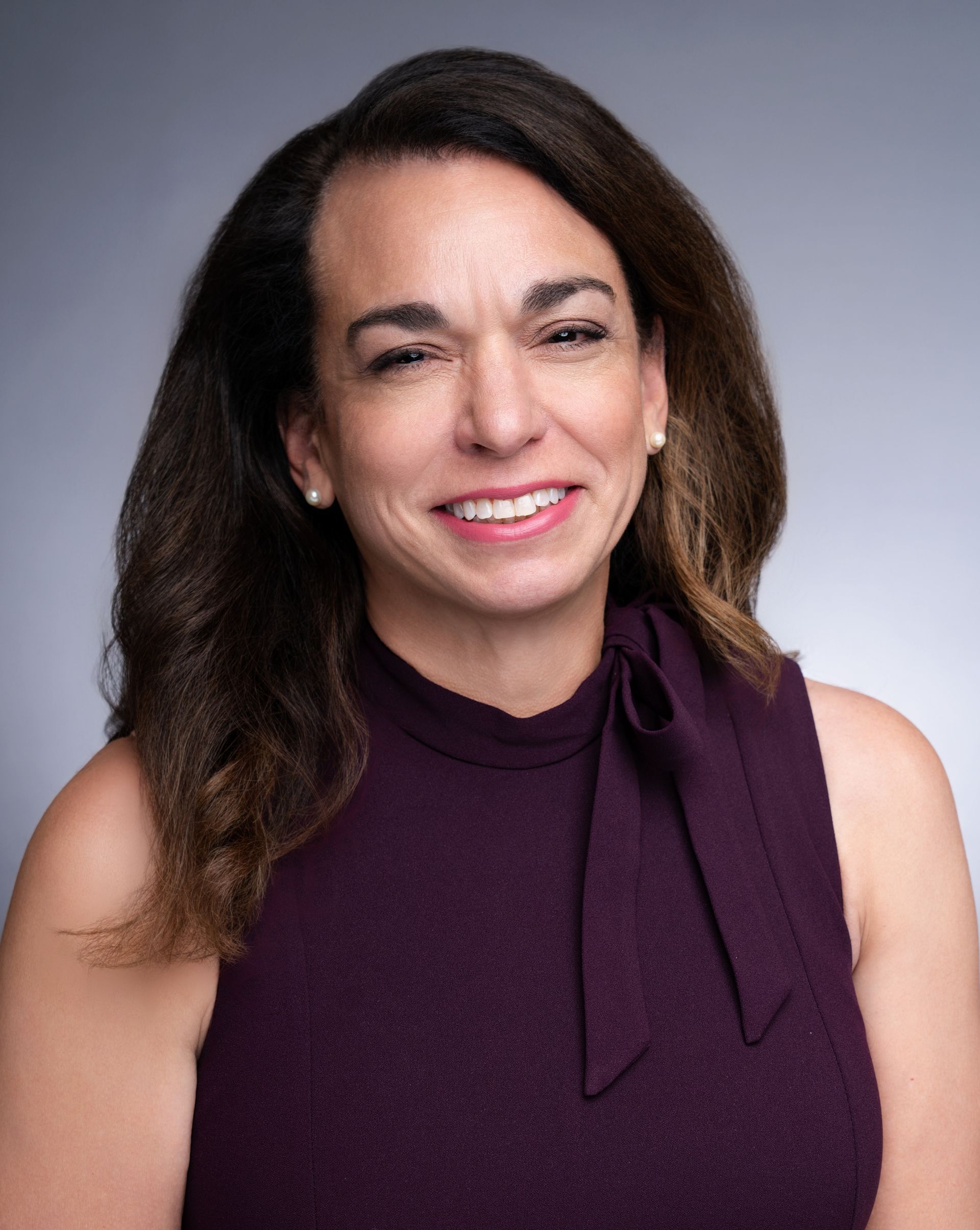 A woman in a purple dress is smiling for the camera.