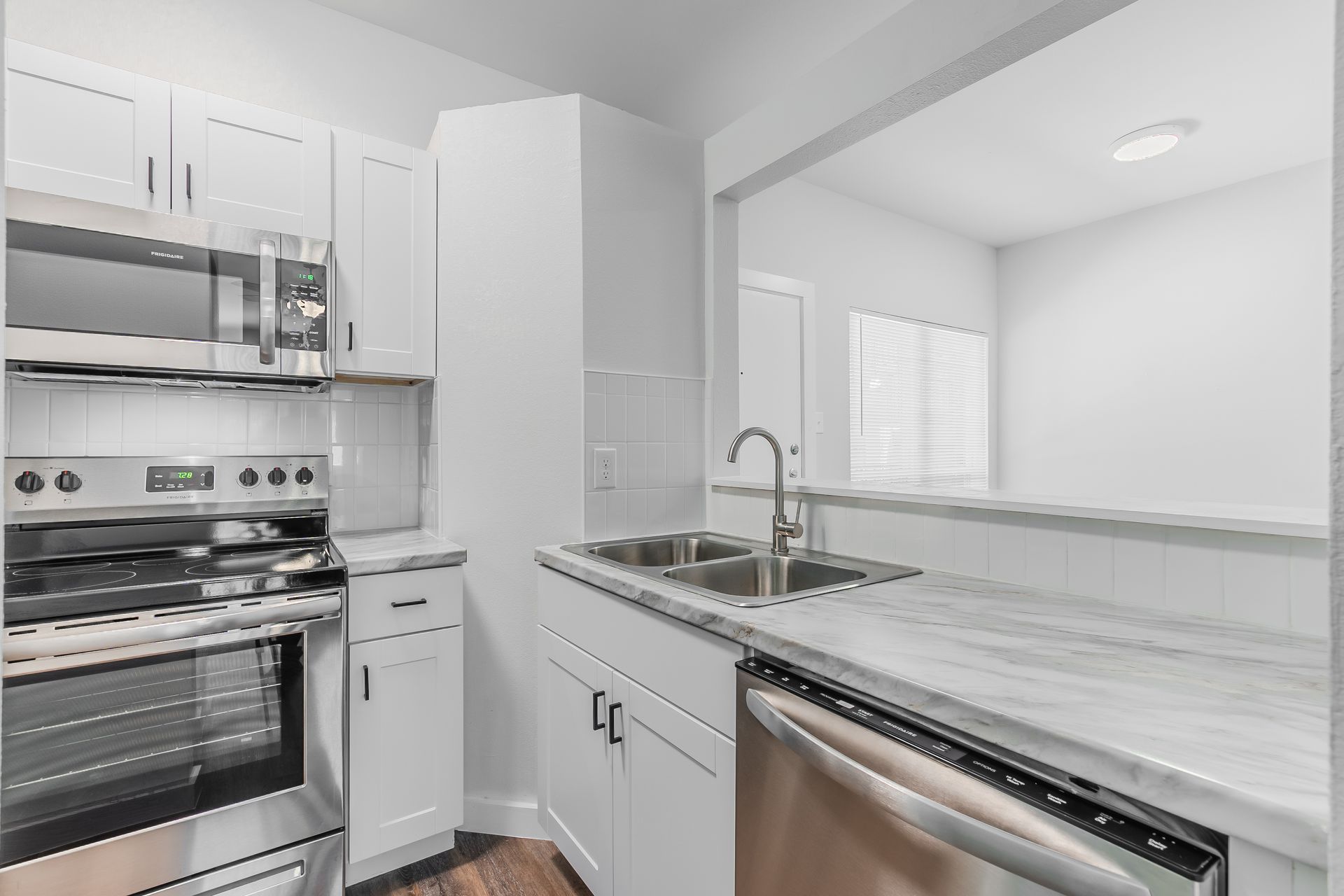 Modern white kitchen with stainless steel appliances, sink, and countertop.