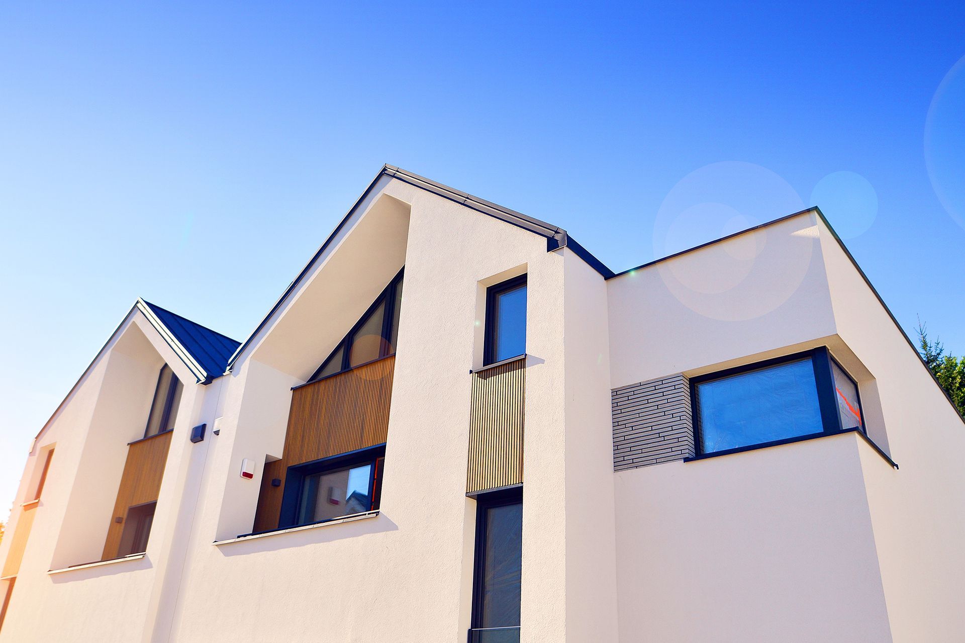 Modern building with red and gray facade, white accents, and a blue sky background.