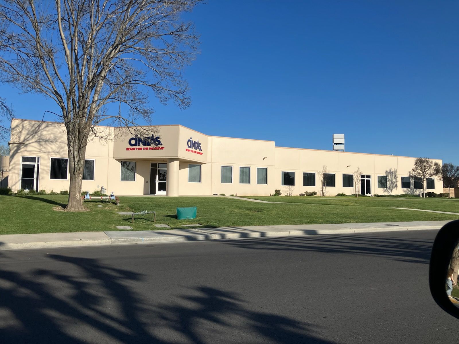 A beige commercial building with red and blue logos, a tree in front, and a blue sky.
