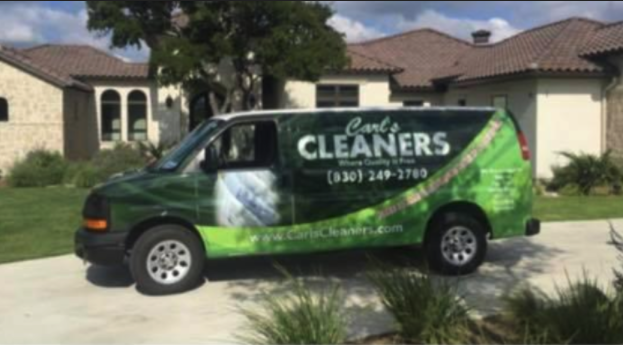 A carl 's cleaners van is parked in front of a house