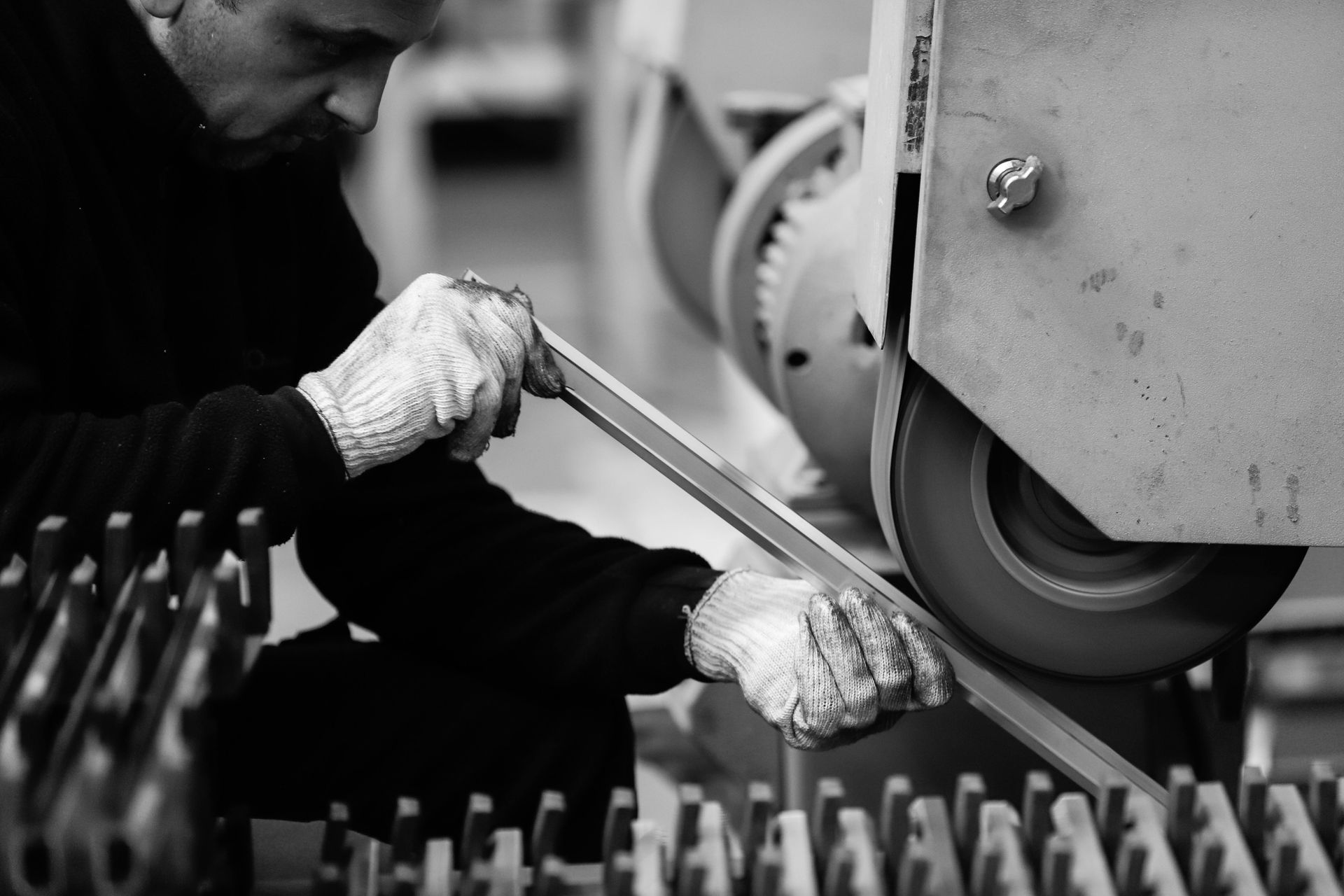 Een fabrieksarbeider met handschoenen aan gebruikt een polijstmachine om een onderdeel te polijsten