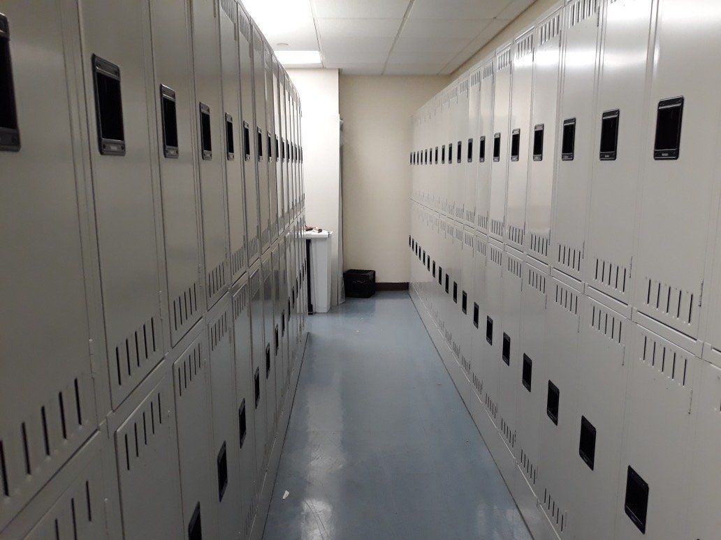 A hallway filled with lots of lockers and a trash can