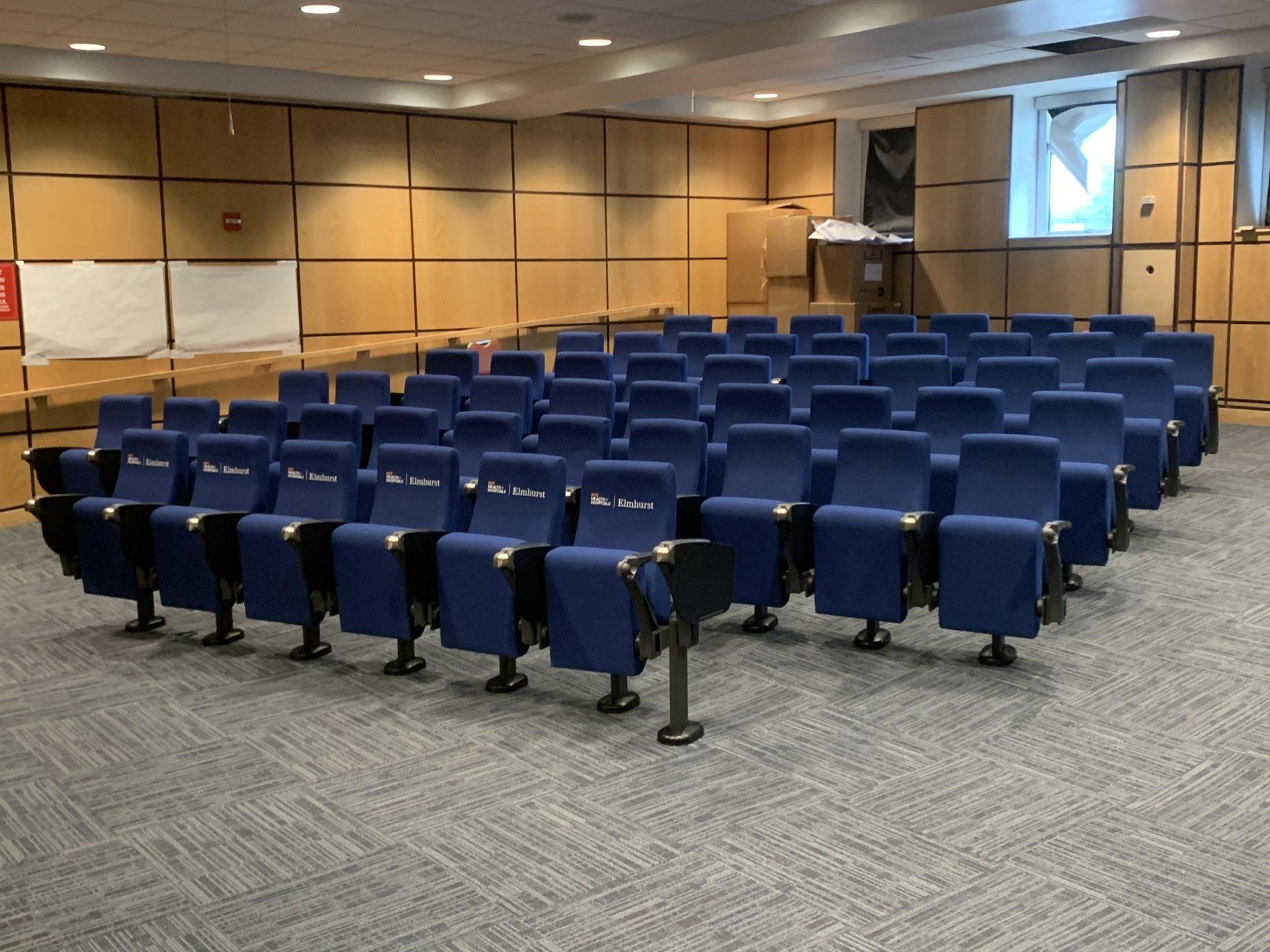Rows of blue chairs are lined up in an auditorium.