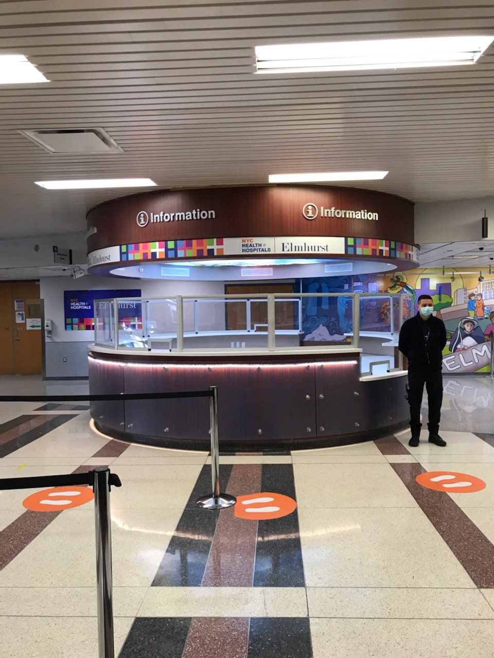 A man wearing a mask stands in front of an information desk