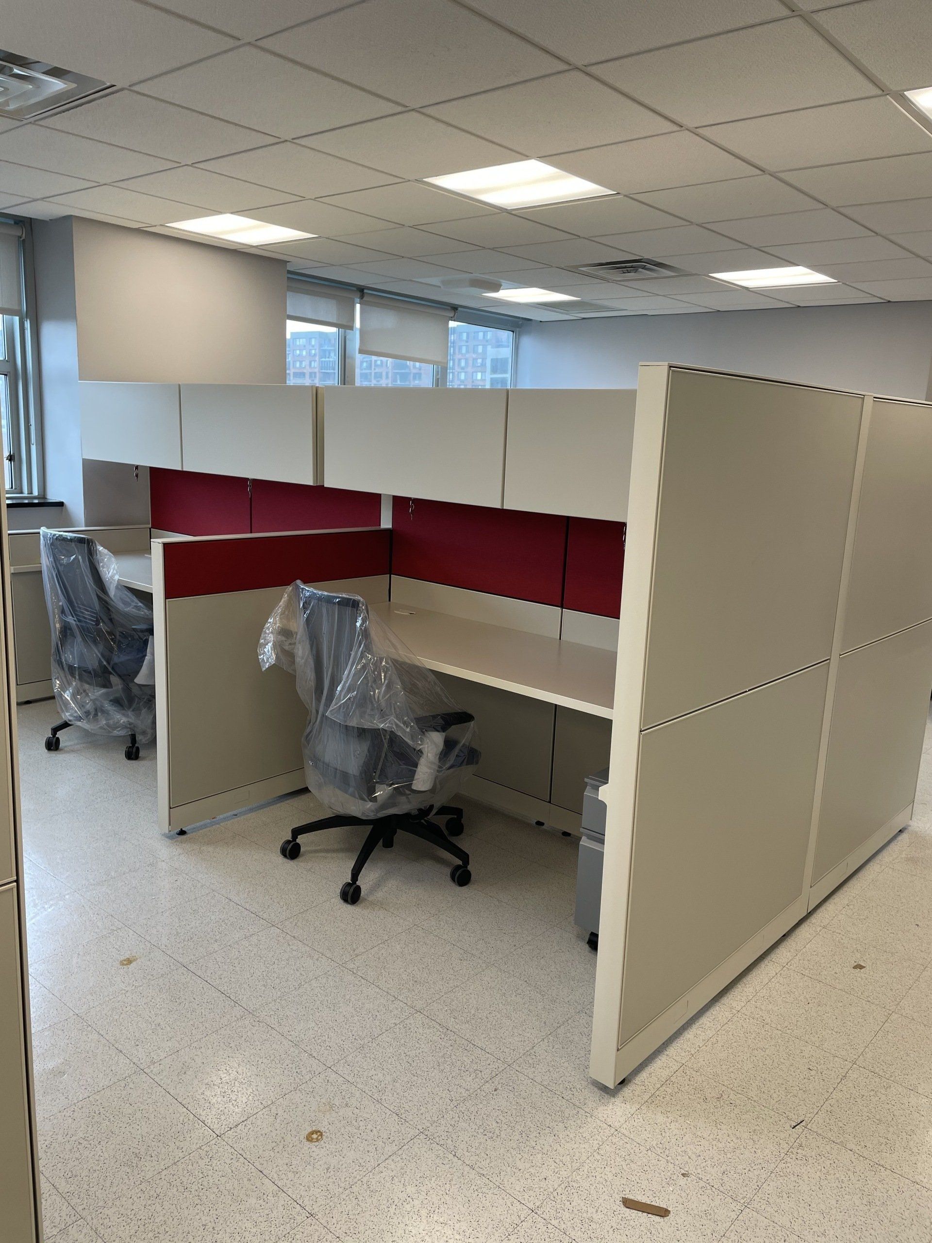 A cubicle with two chairs and a desk