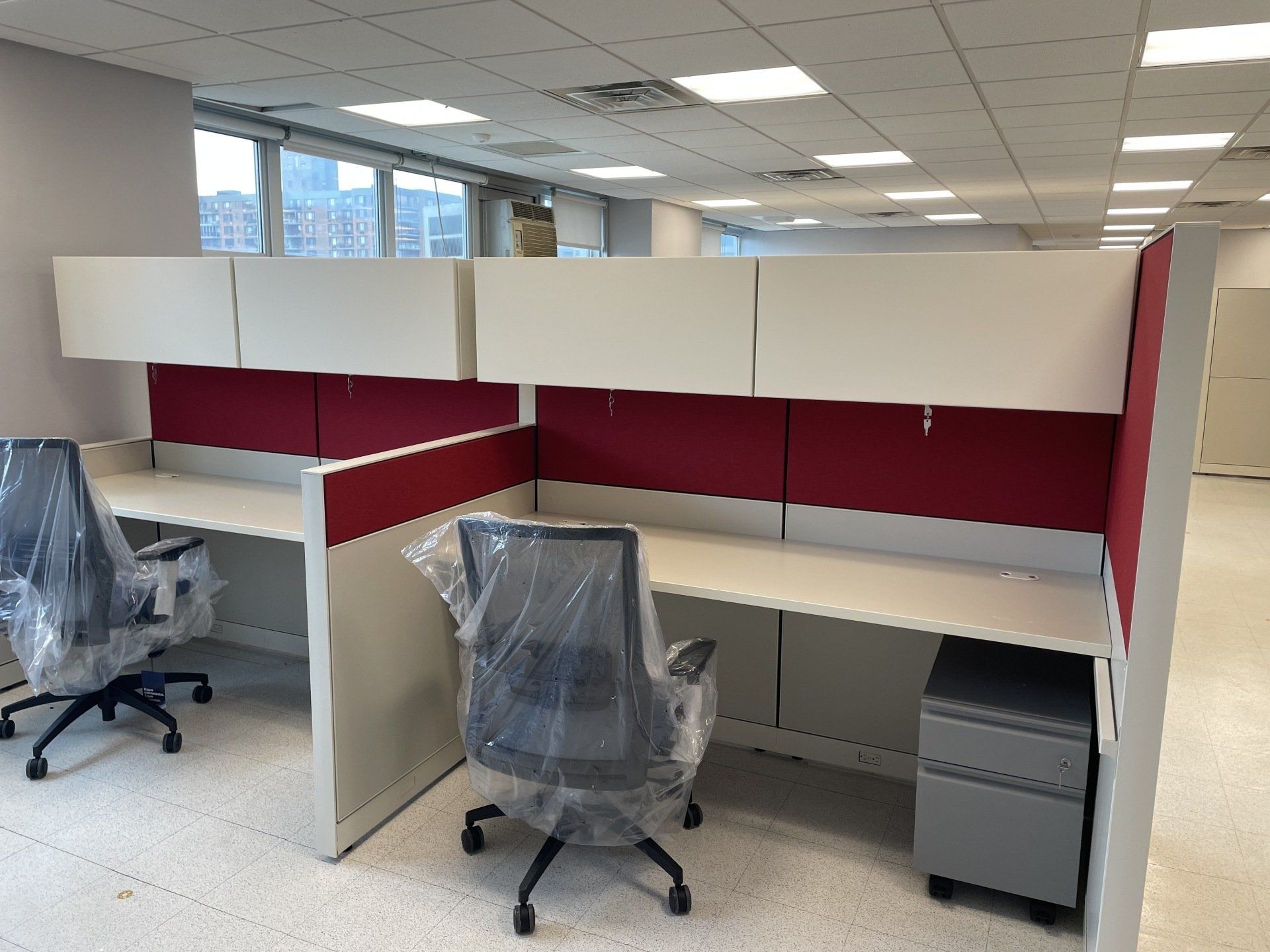 A cubicle with two desks and two chairs in an office.