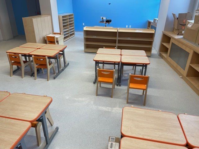 A classroom with wooden tables and orange chairs