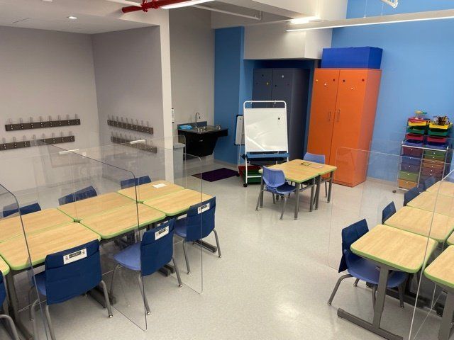 A classroom with tables and chairs and a white board