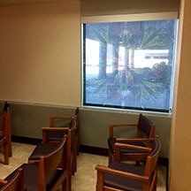A waiting room with wooden chairs and a large window.