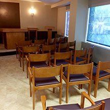 A row of wooden chairs in a room with a window.