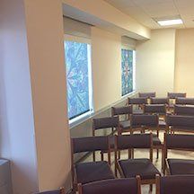 A room filled with rows of chairs and windows.
