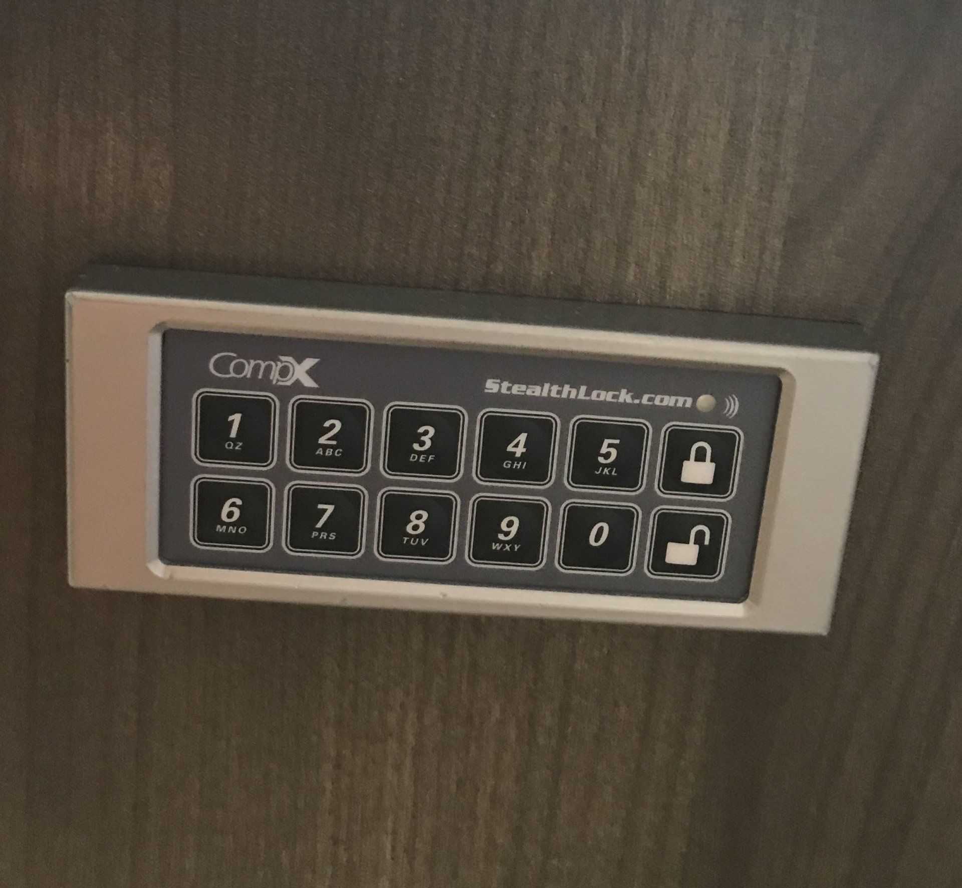 A close up of a stealthlock keypad on a wooden door