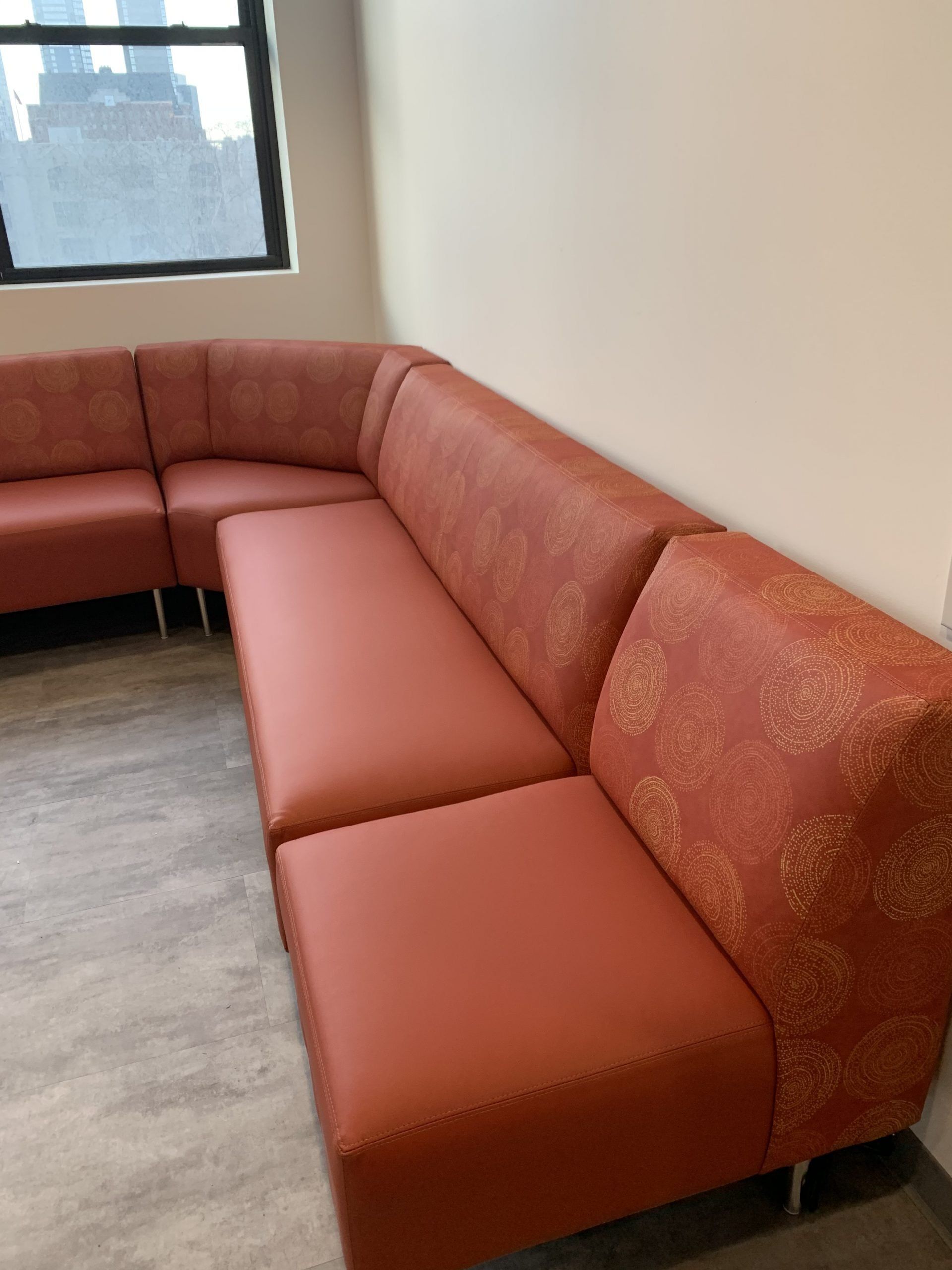 An orange sectional couch in a room with a window