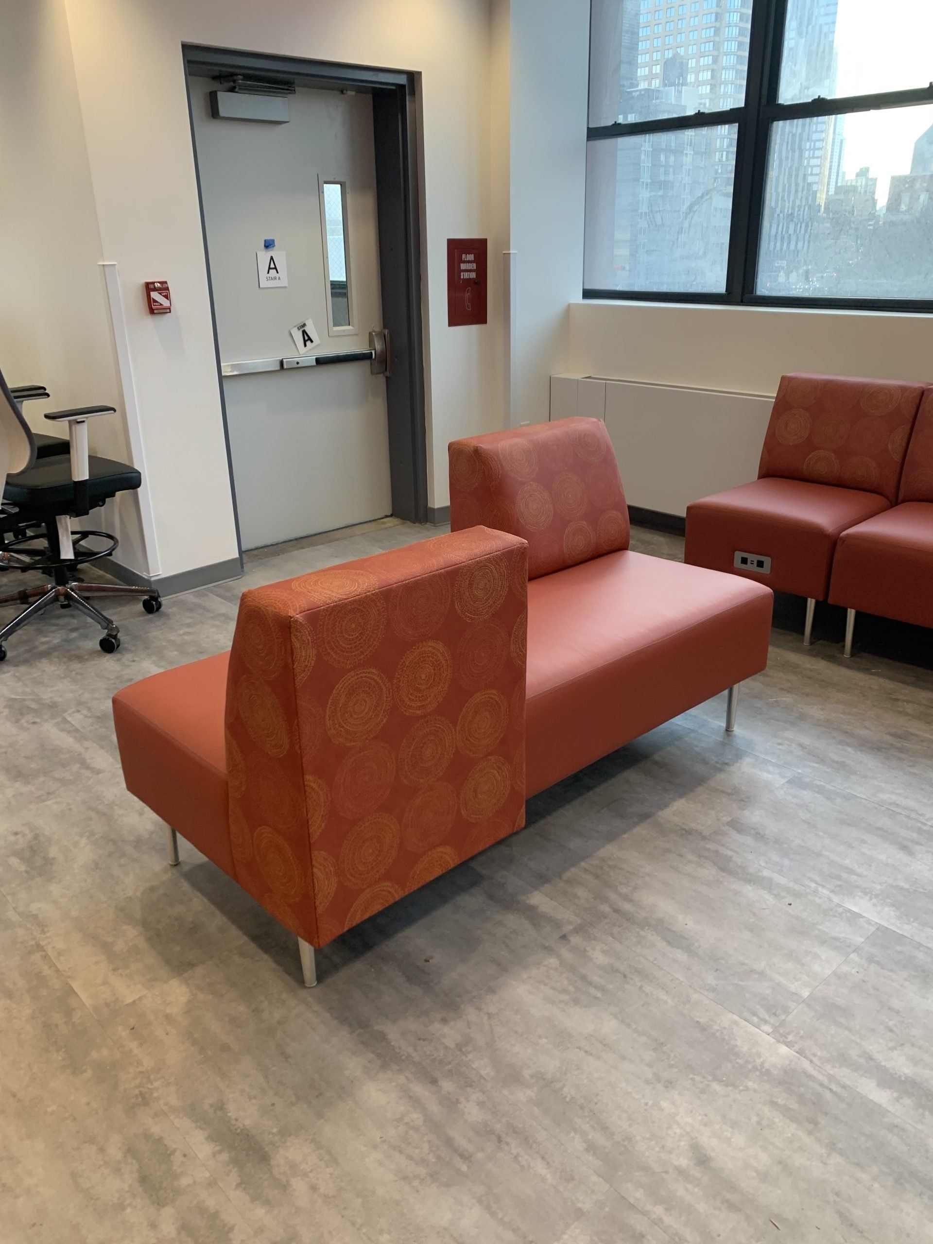 A waiting room with a red couch and chairs