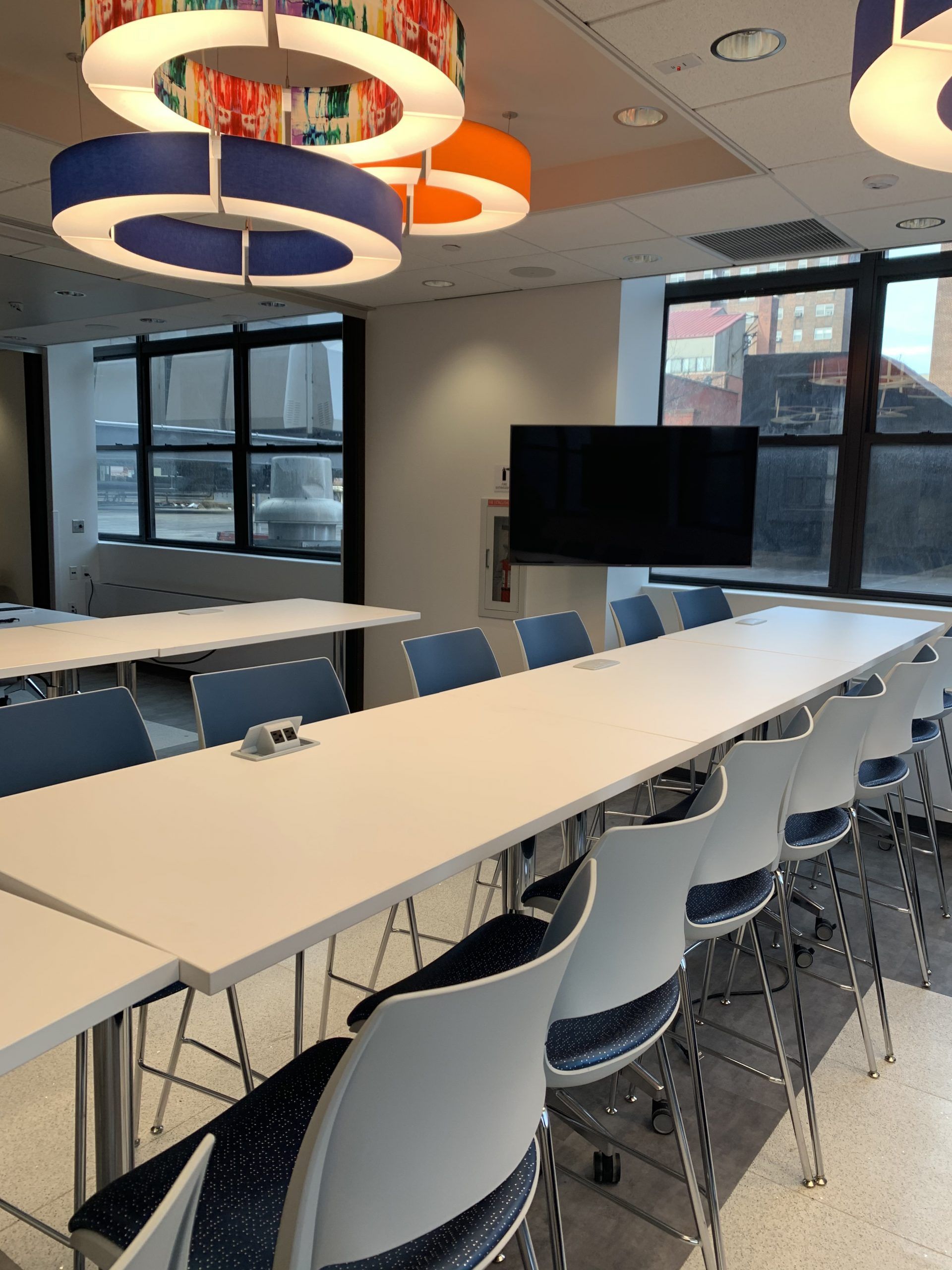 A conference room with tables and chairs and a flat screen tv