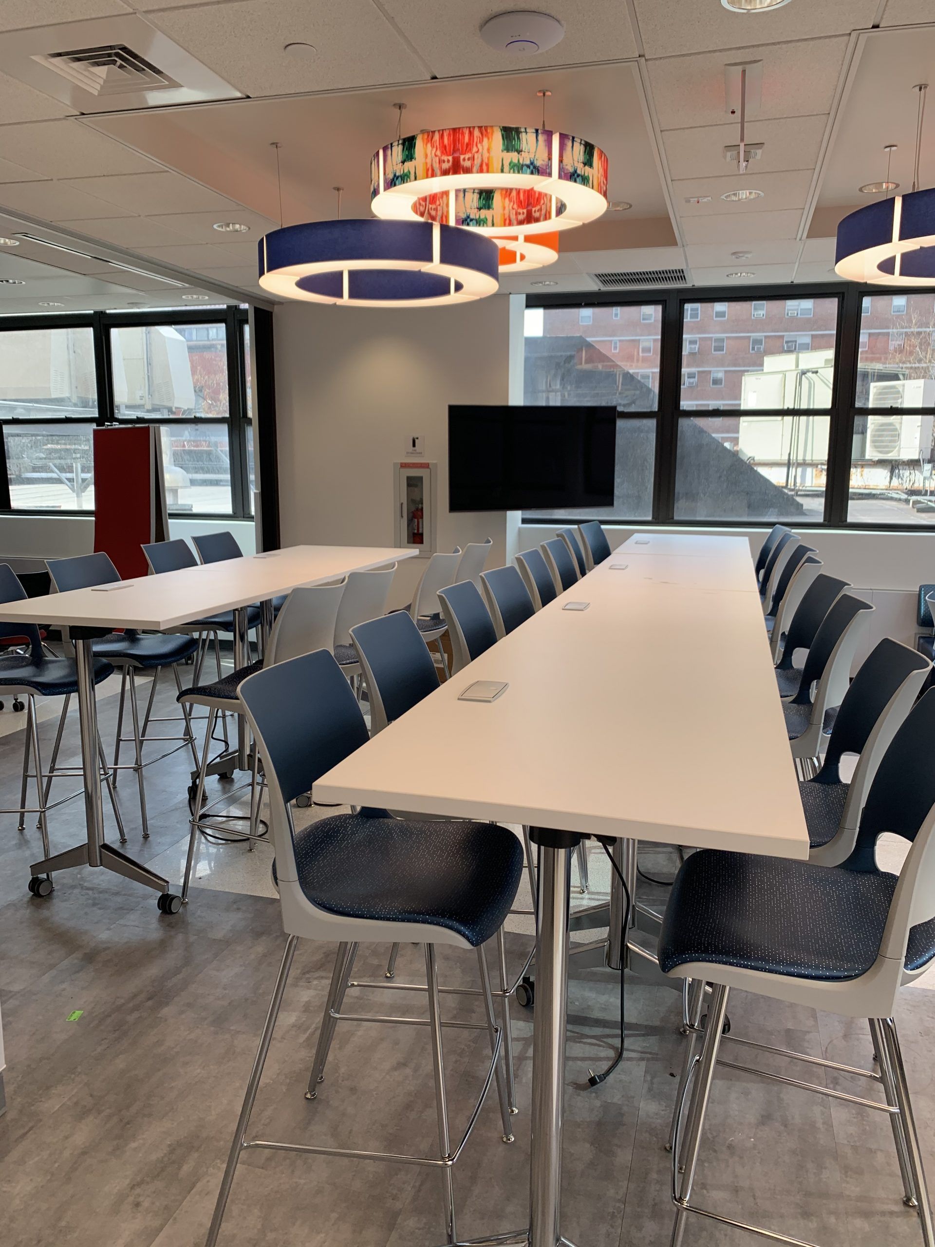 A conference room with tables and chairs and a flat screen tv
