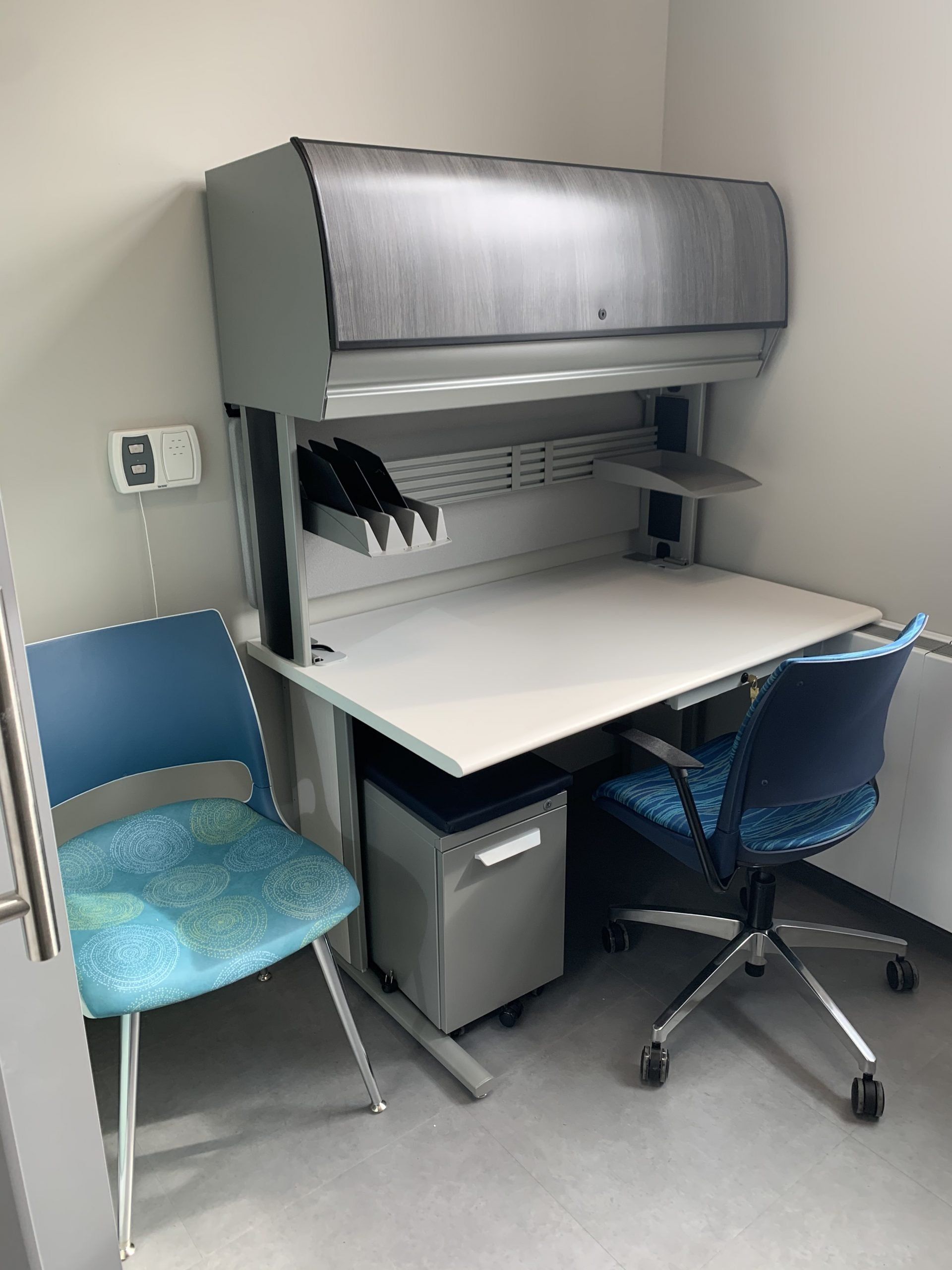 A white desk with a blue chair in a room.