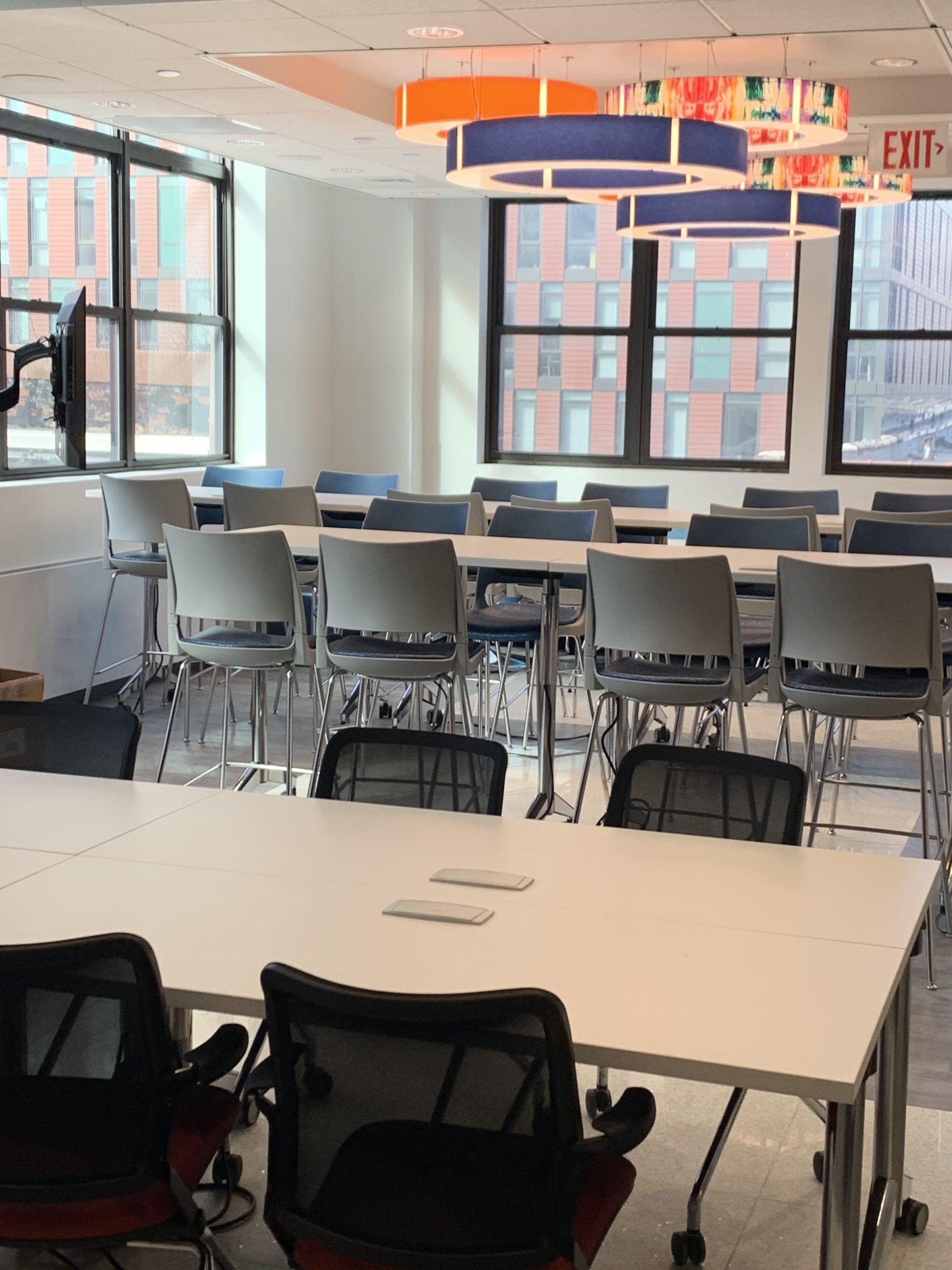 A large room with tables and chairs and an exit sign