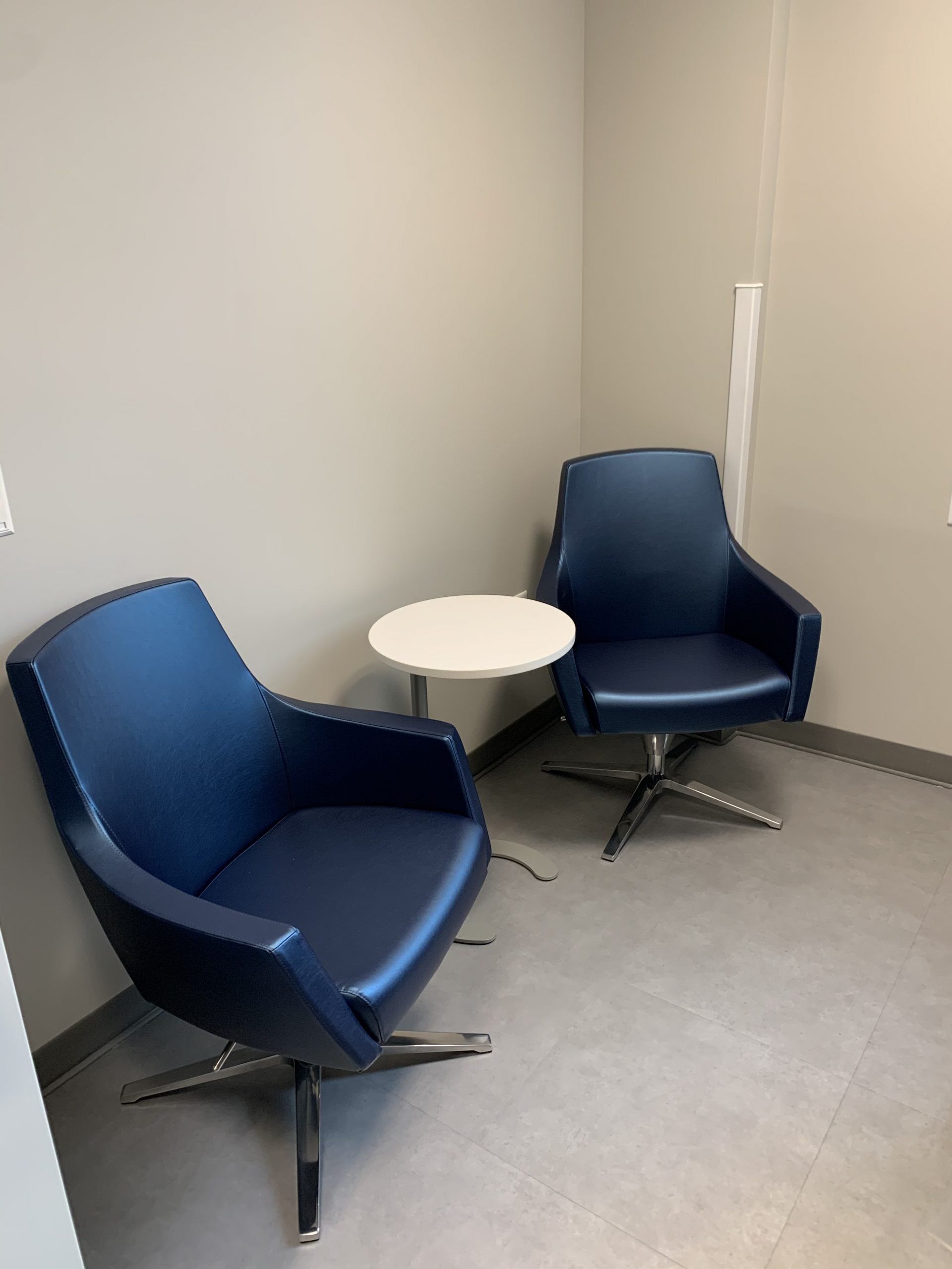 Two blue chairs and a white table in a room.
