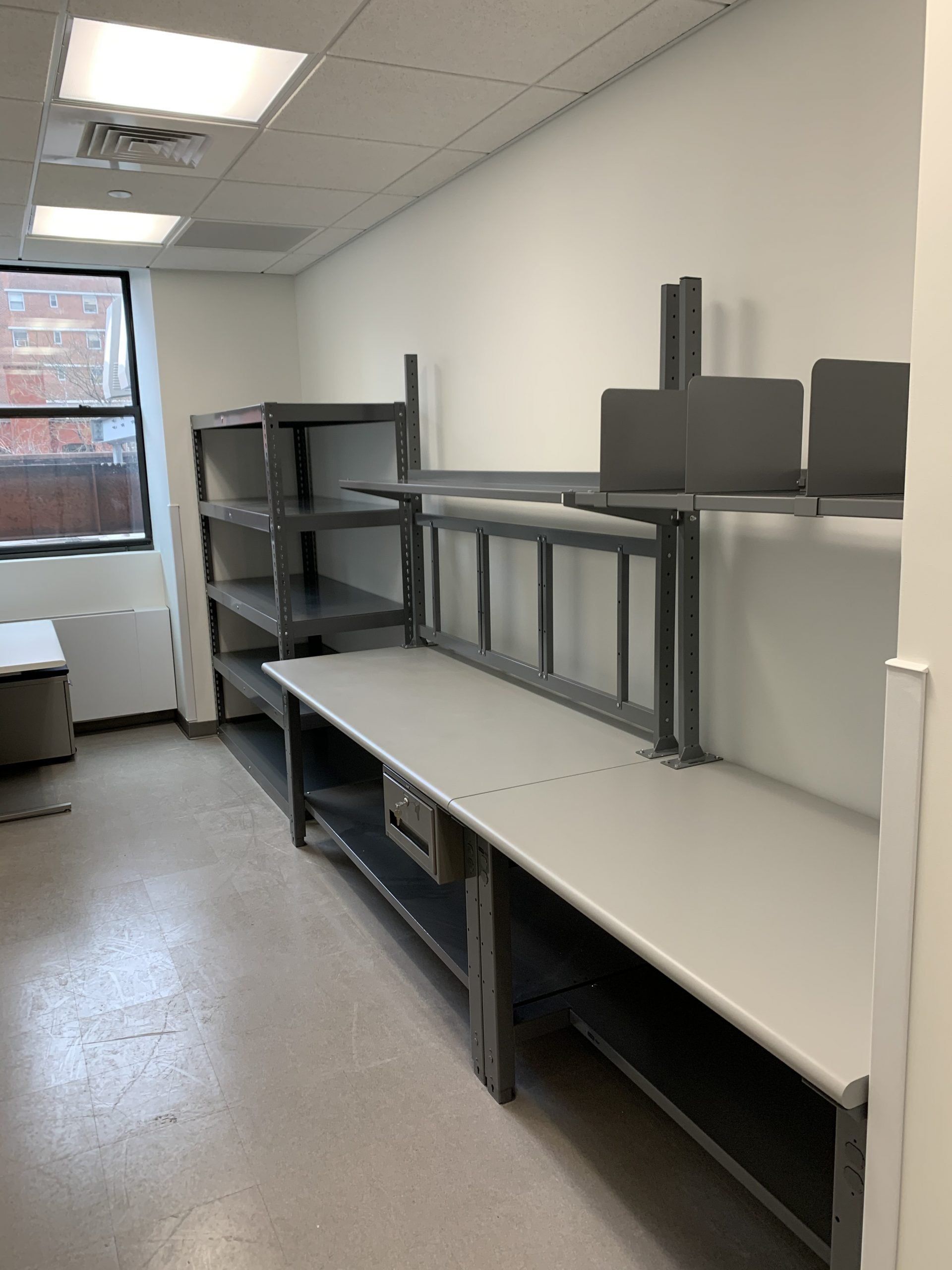 An empty room with shelves and tables and a window