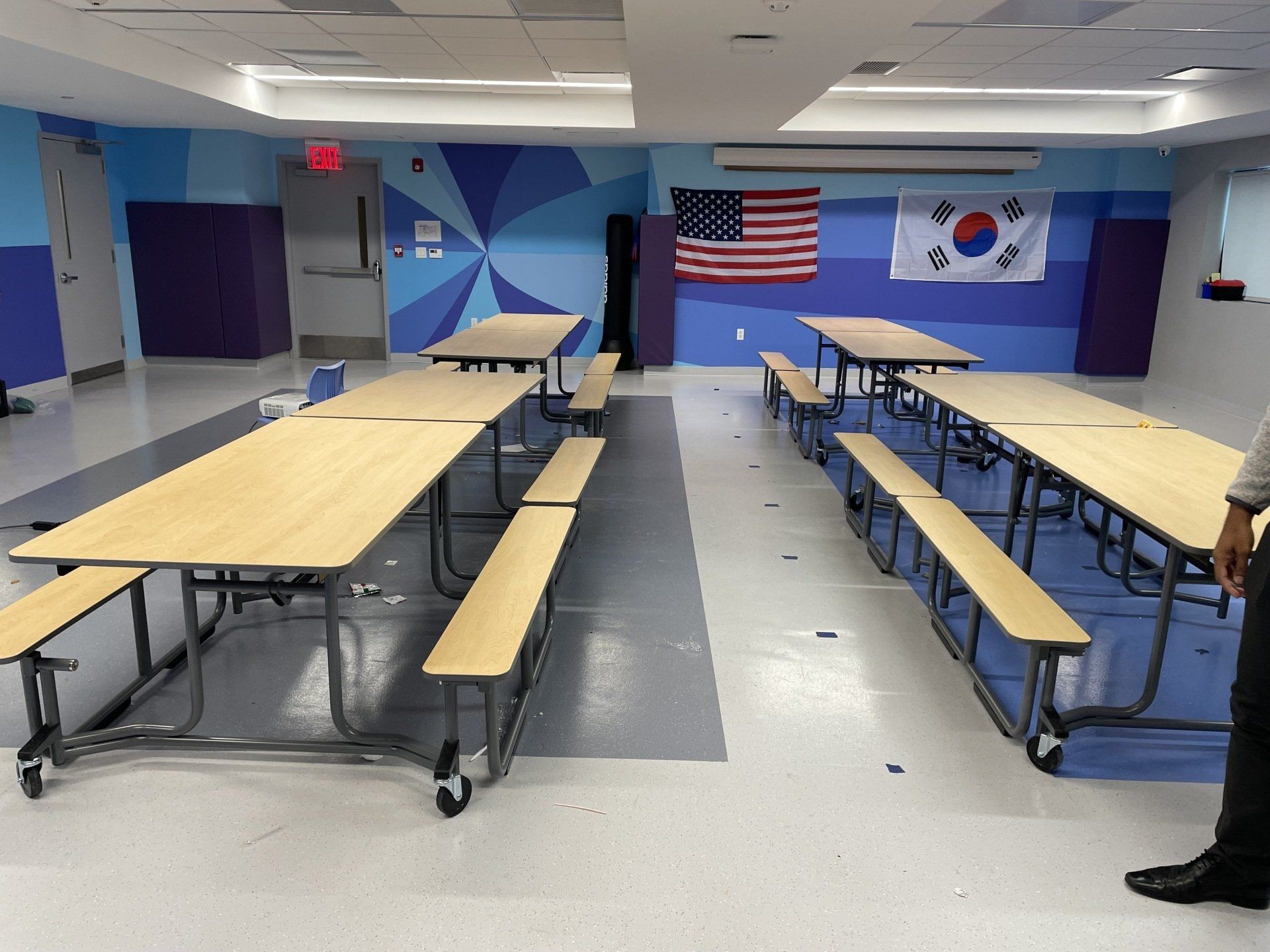 A man standing in a room with tables and benches