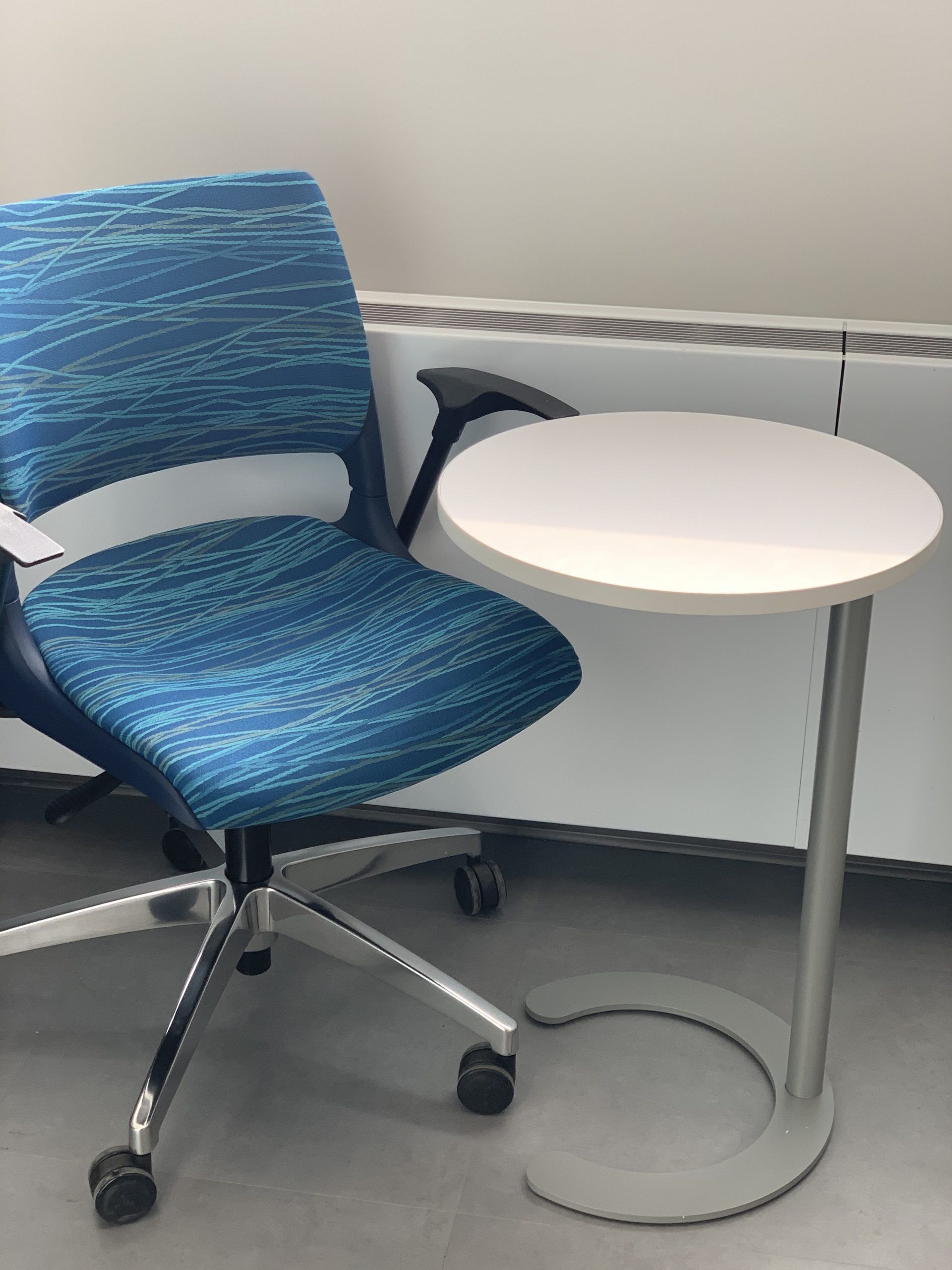 A blue office chair sits next to a small white table