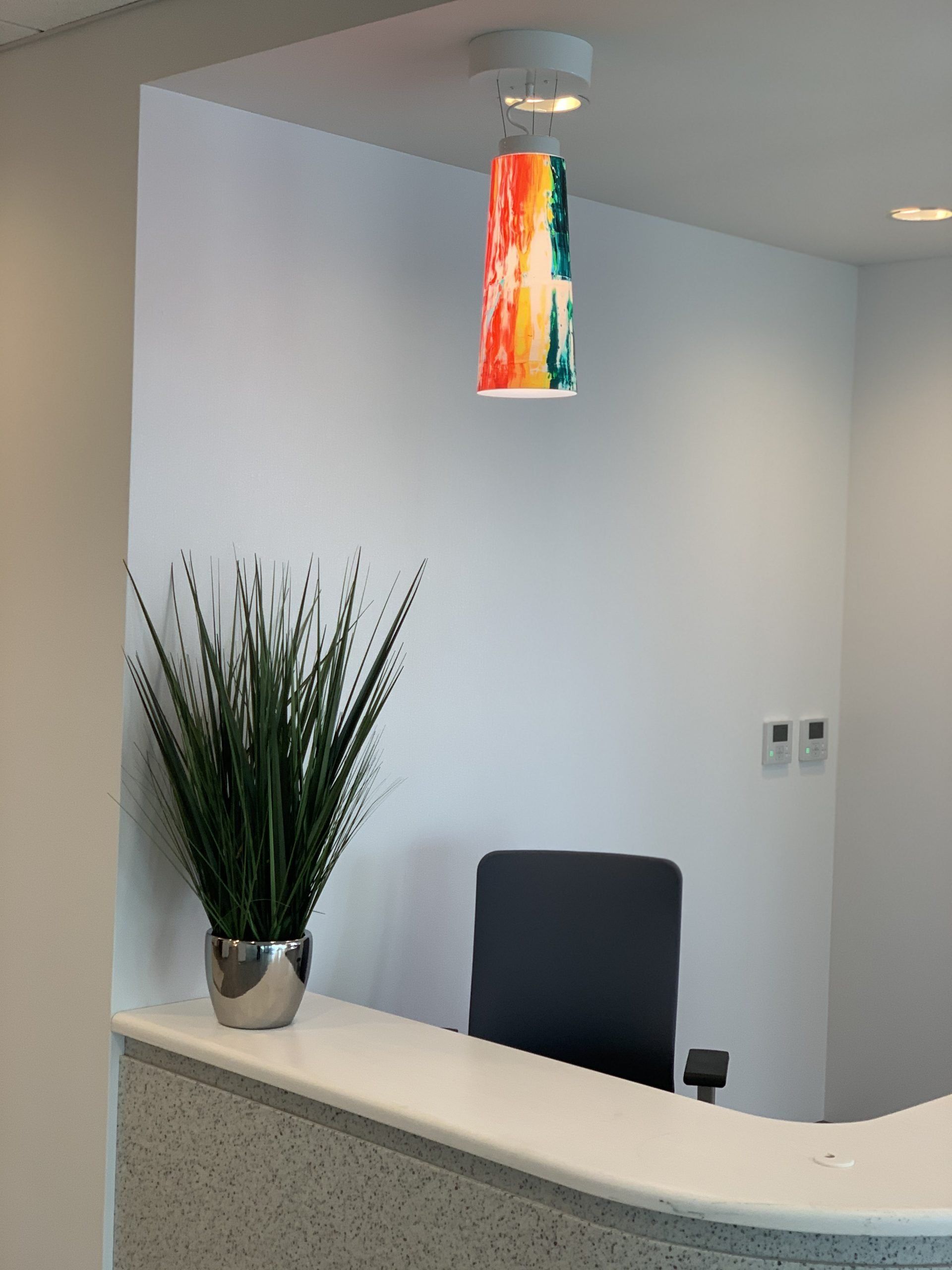 A colorful lamp hangs from the ceiling above a desk