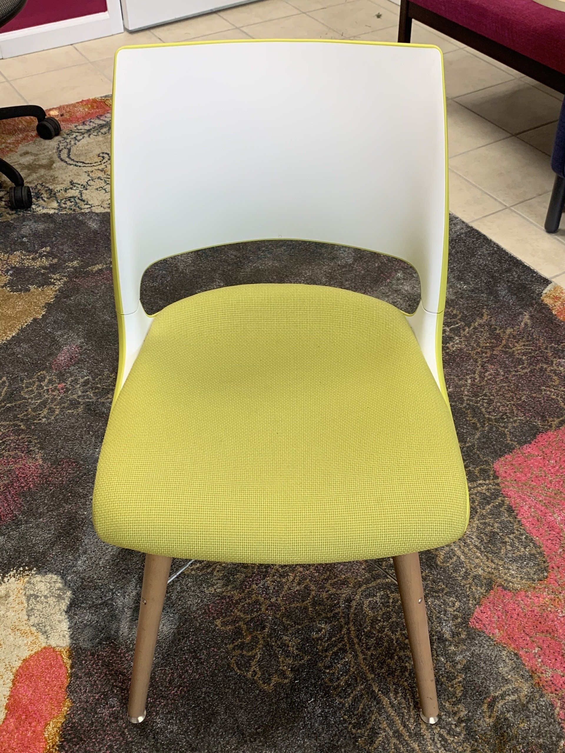 A white chair with a yellow seat sits on a rug