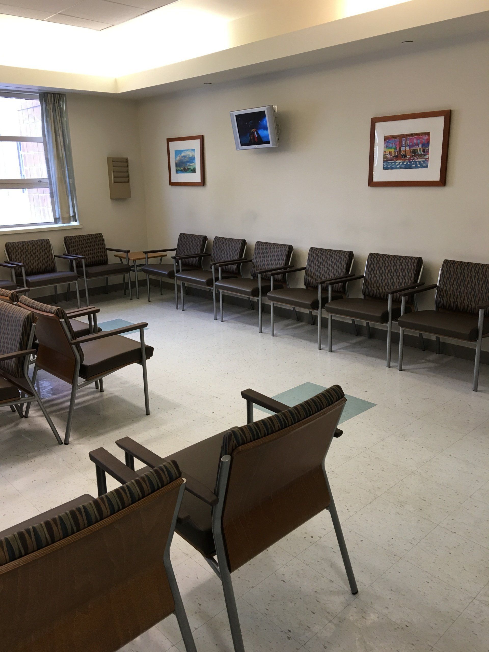 A waiting room with chairs and a television on the wall