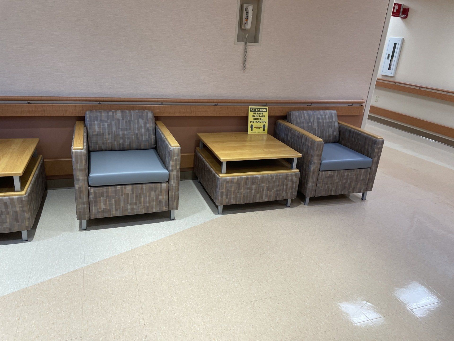 A row of chairs and tables in a hospital waiting room.