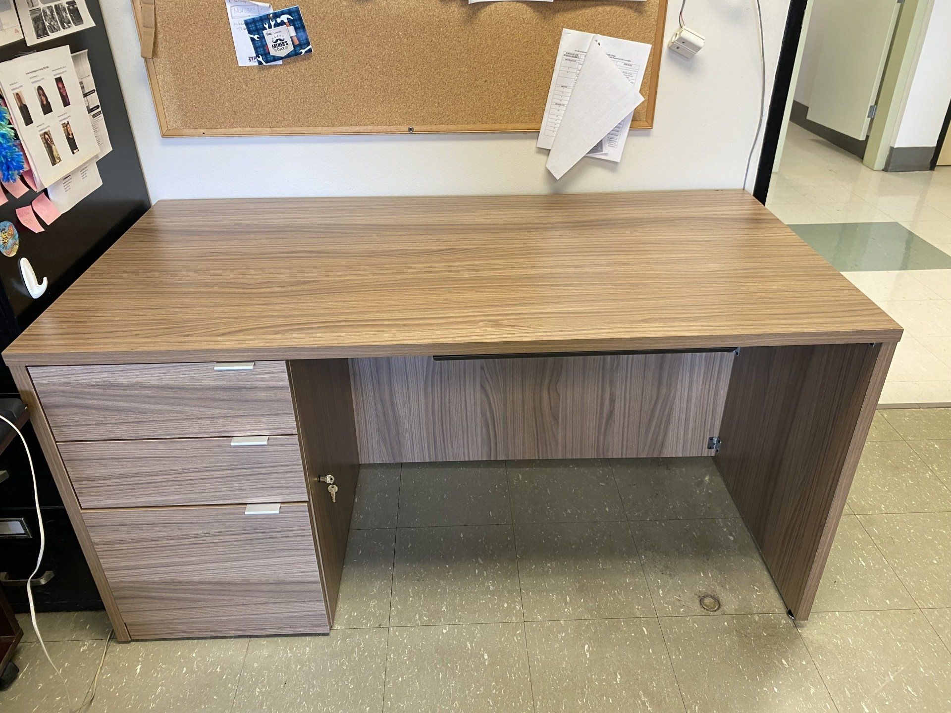 A wooden desk with a cork board behind it