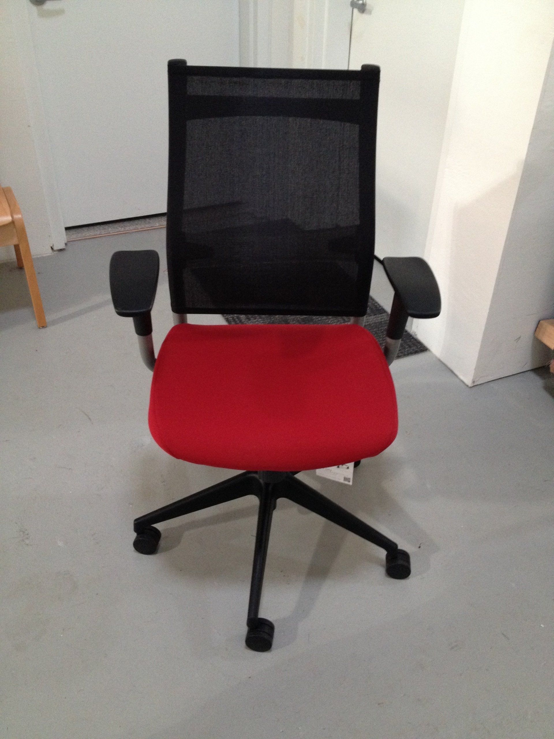 An office chair with a red seat and black mesh back