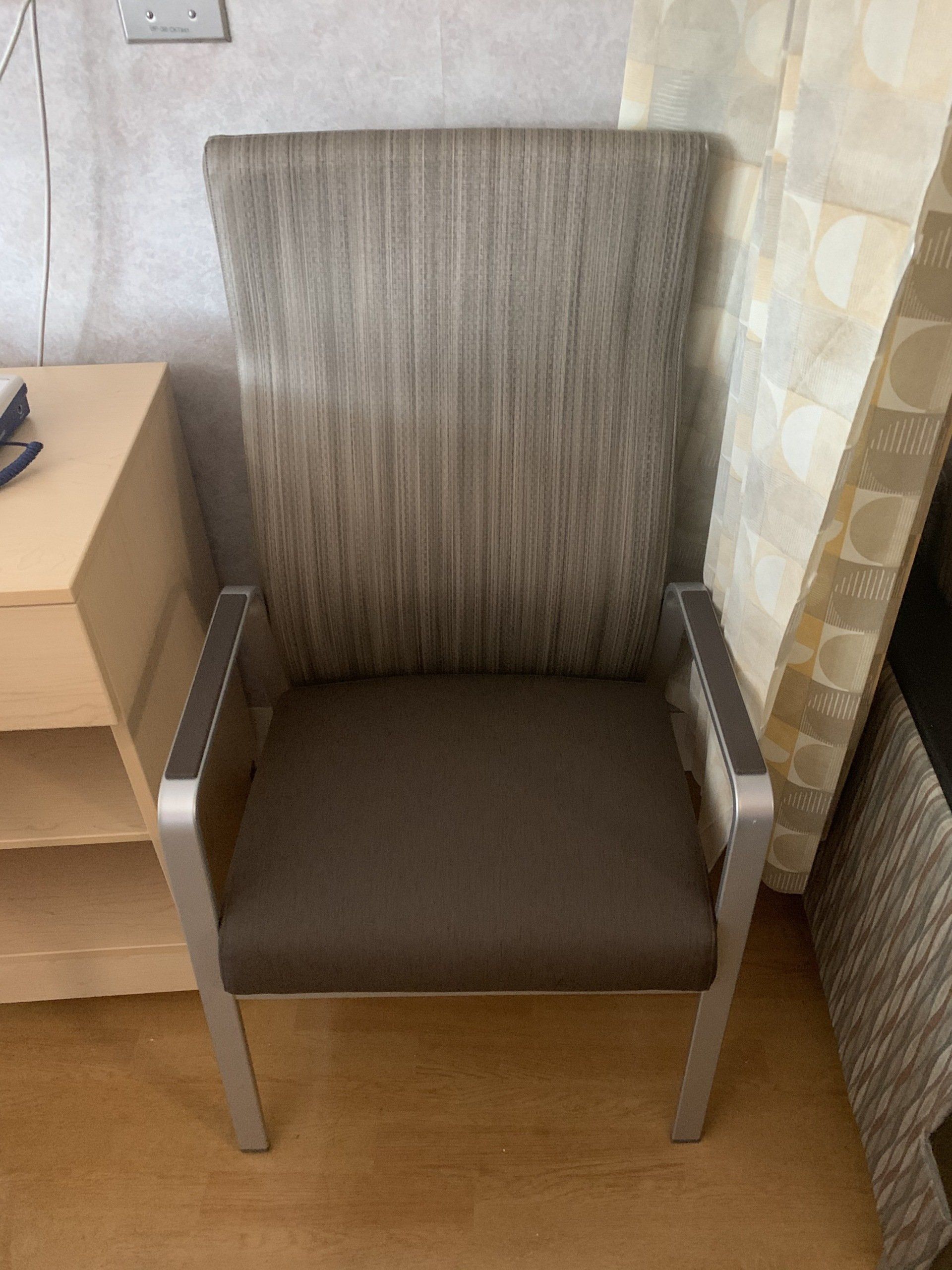 A chair is sitting in a room next to a nightstand.