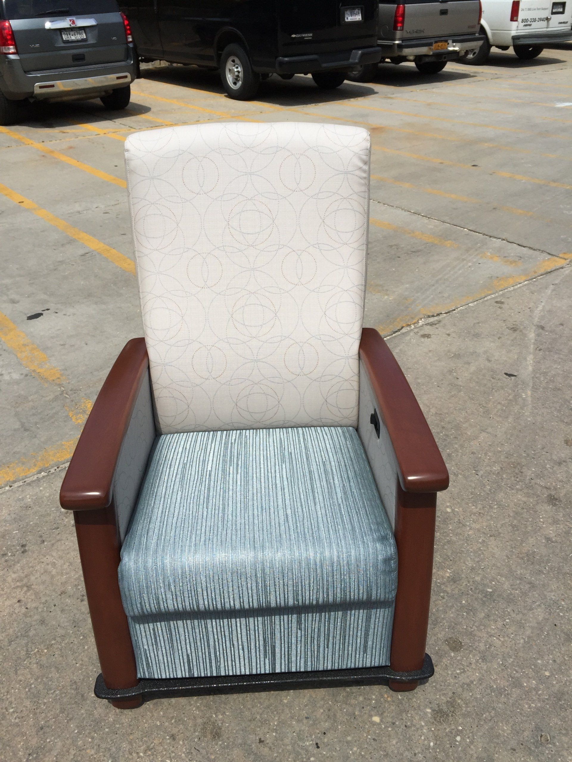 A chair in a parking lot with cars parked behind it