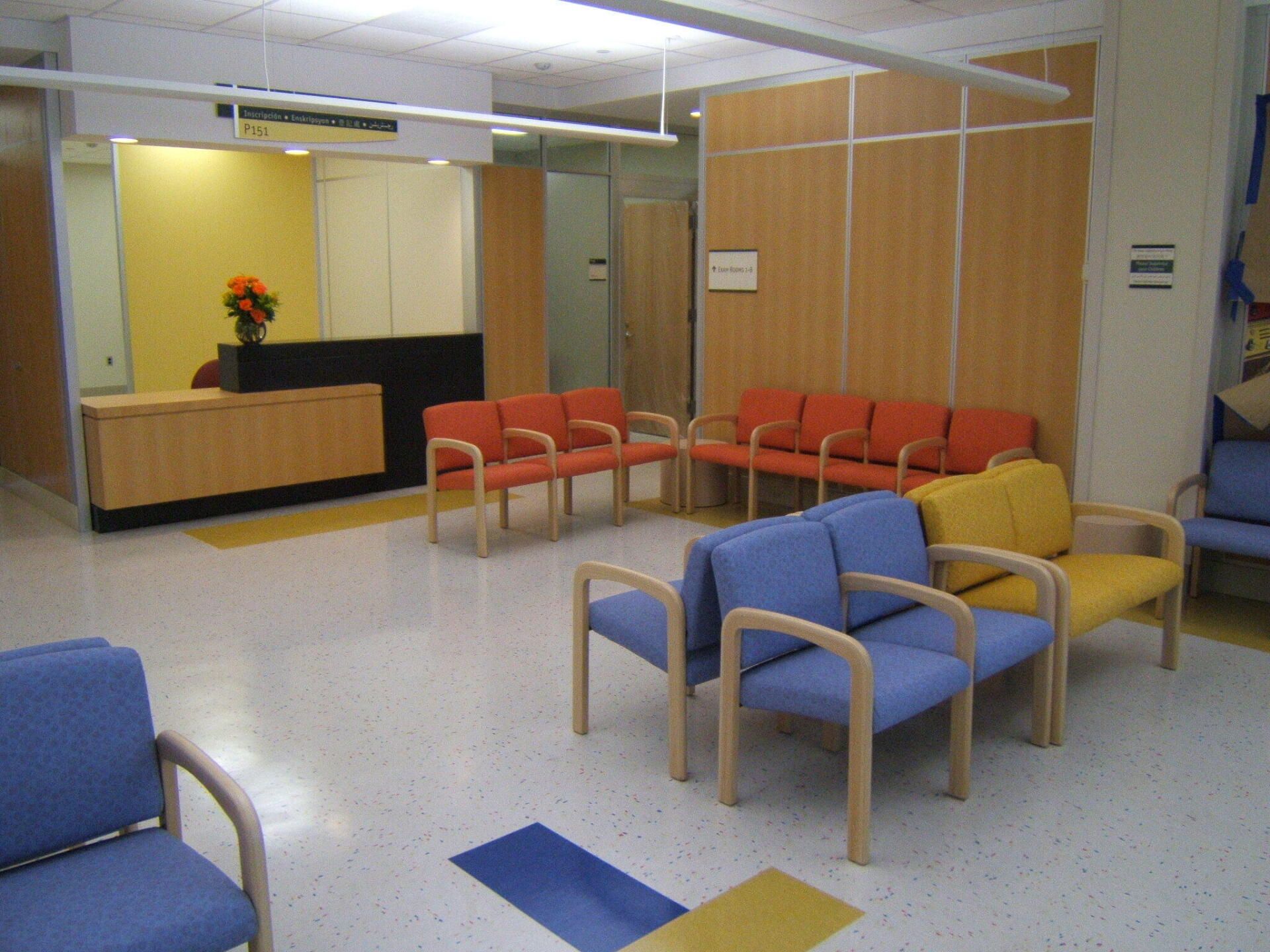 A waiting room with blue chairs and orange chairs