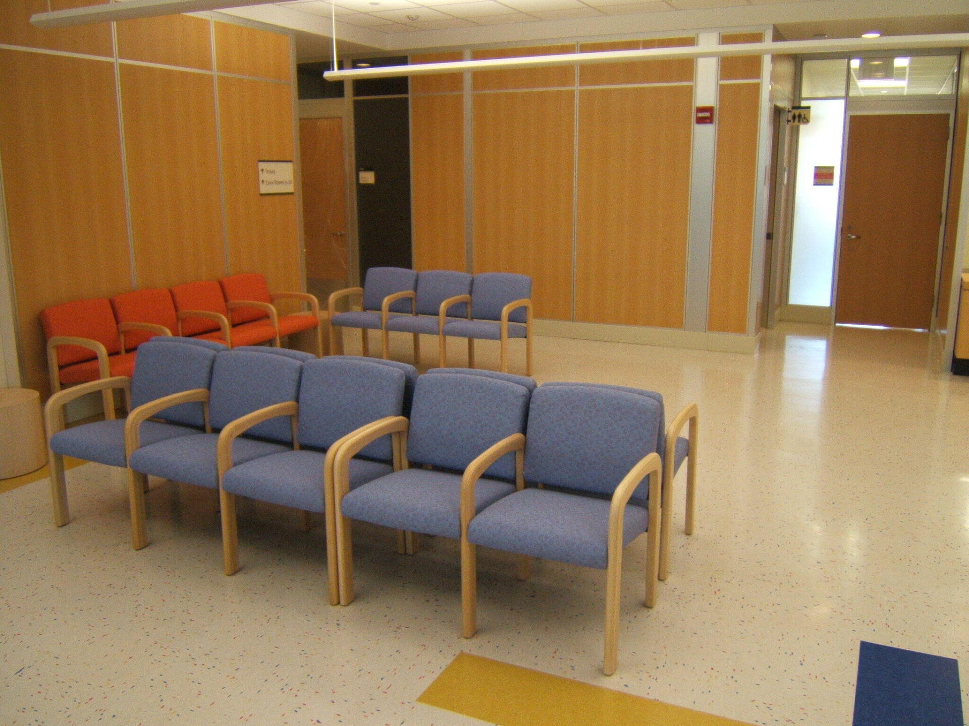 A waiting room with blue chairs and orange chairs