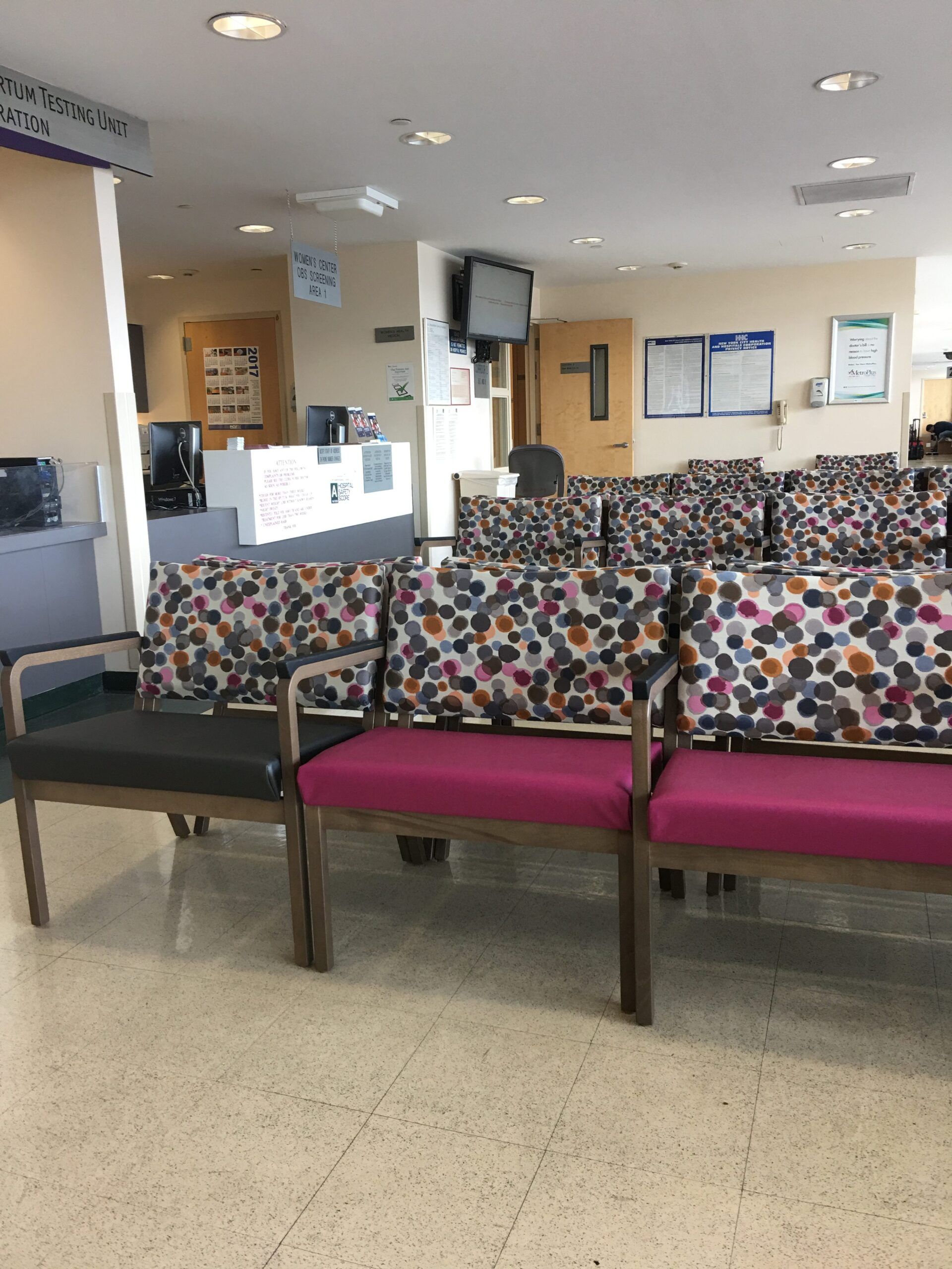 A hospital waiting room with pink and black chairs