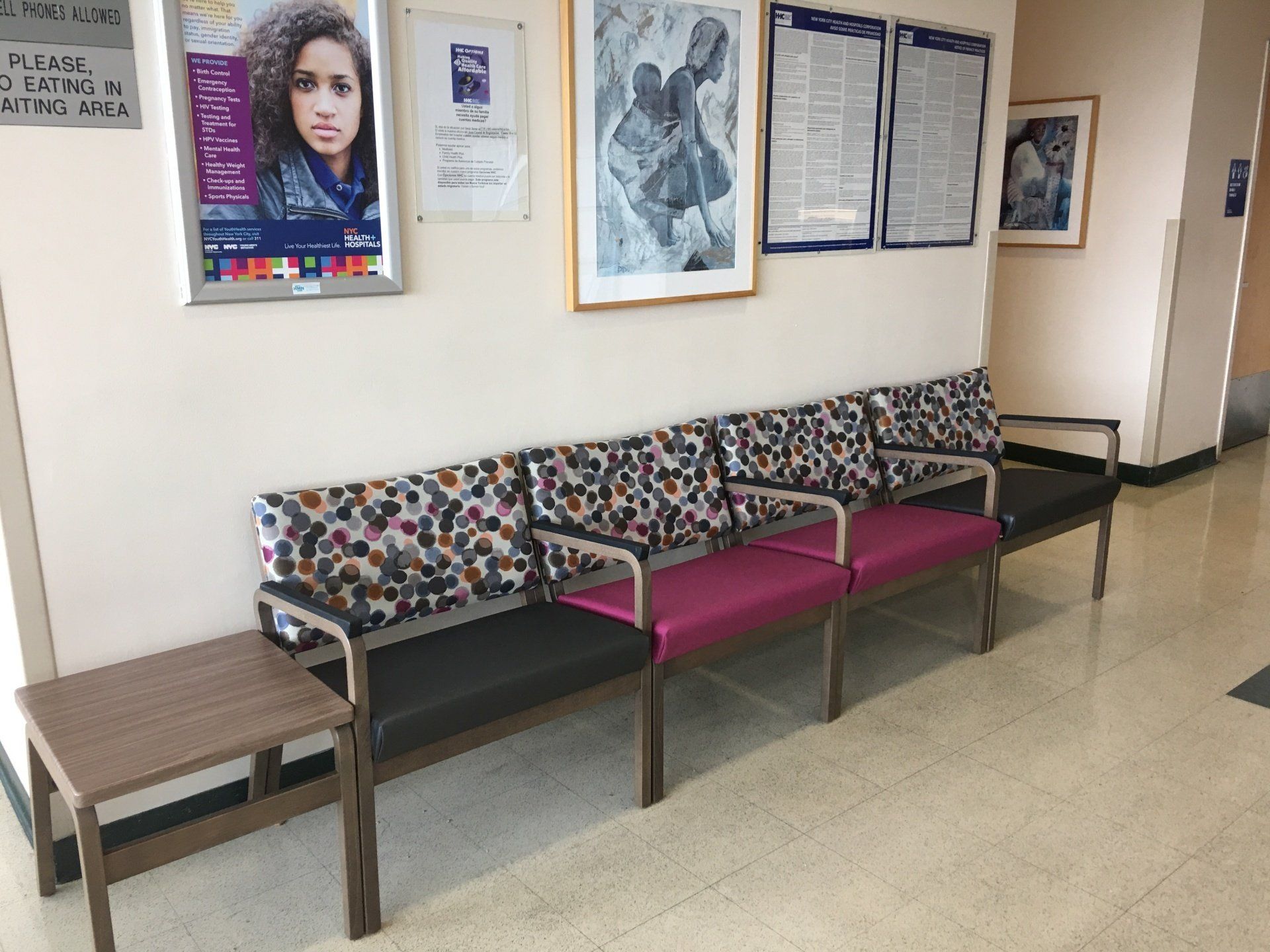 A waiting room with a row of colorful chairs and a table.