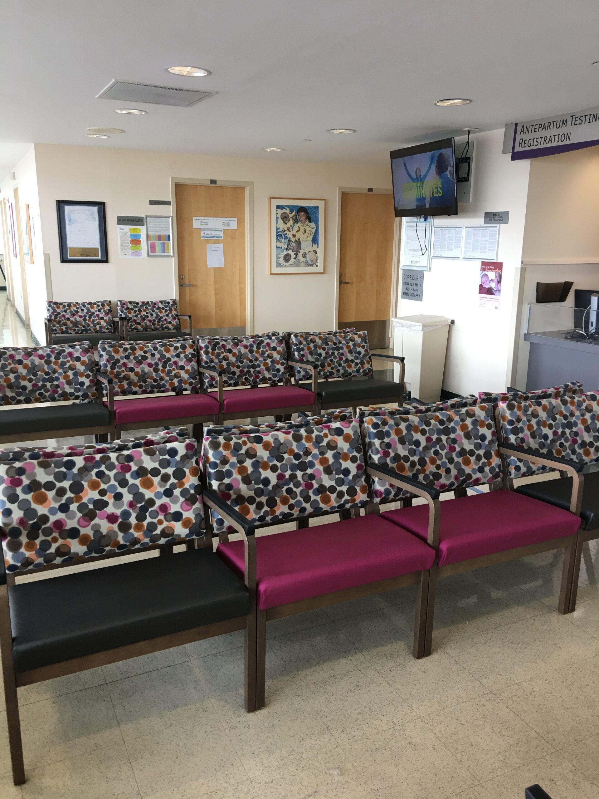 A waiting room with colorful chairs and a tv