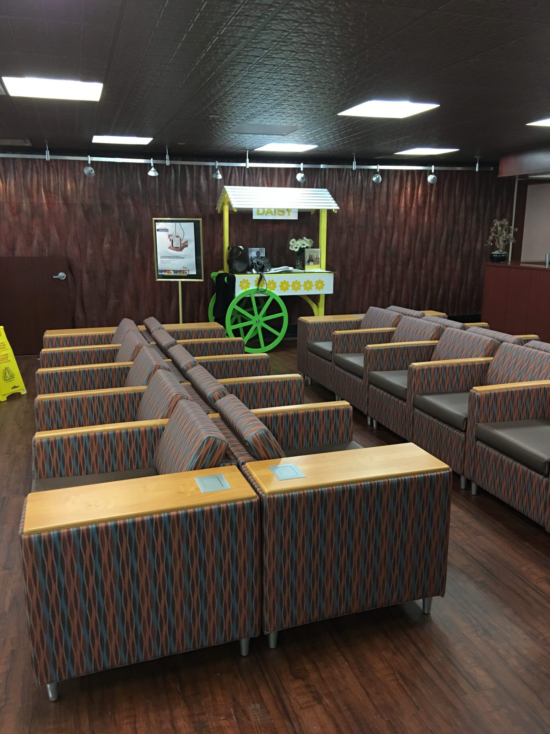 A row of chairs in a room with a cart in the background