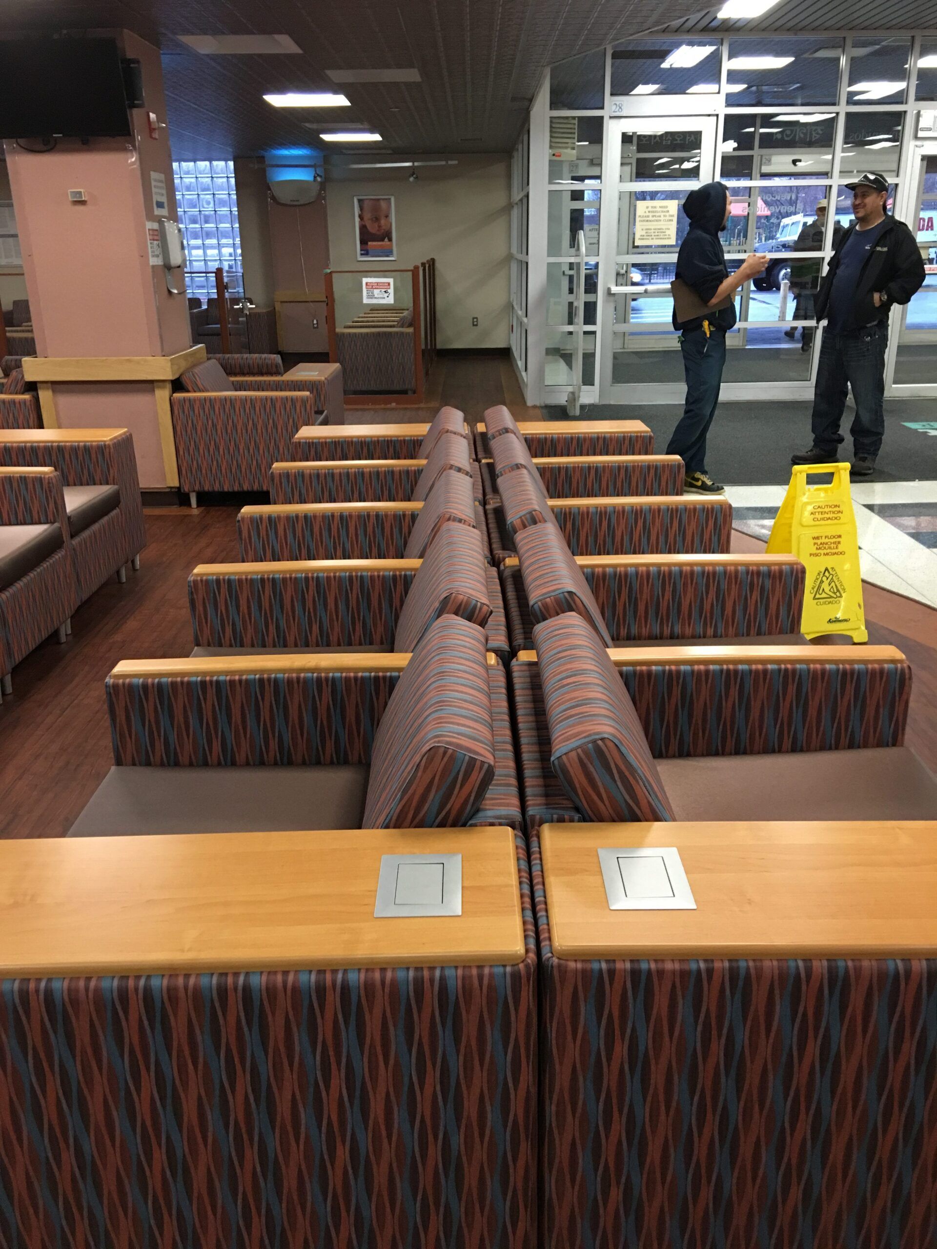 A yellow wet floor sign is on the floor in a waiting room