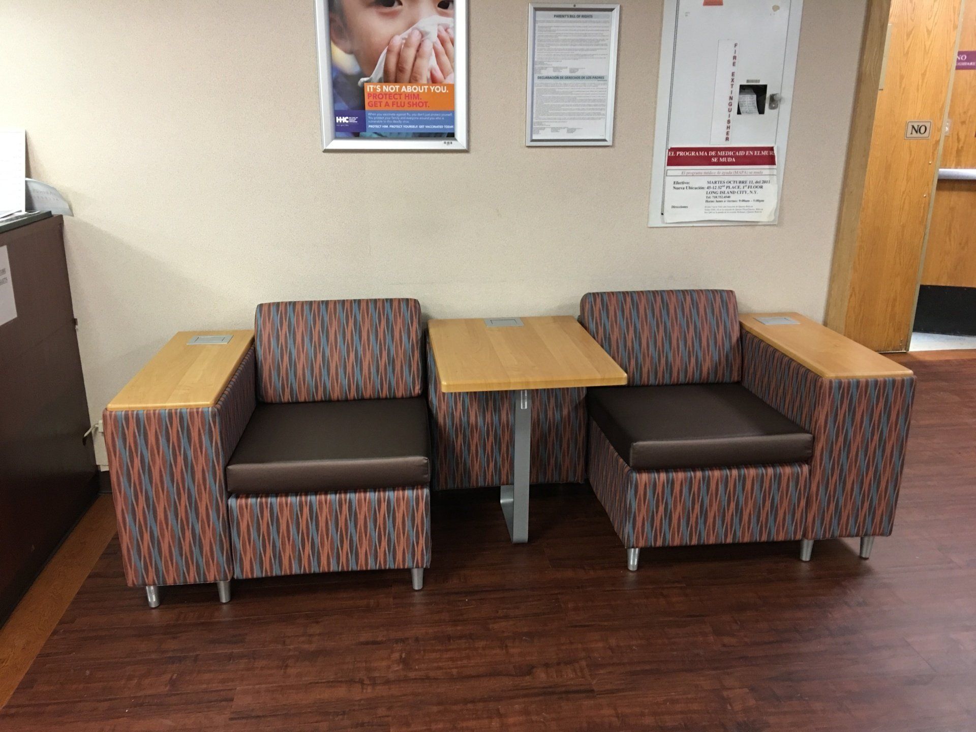 A waiting room with chairs and tables and a poster on the wall.